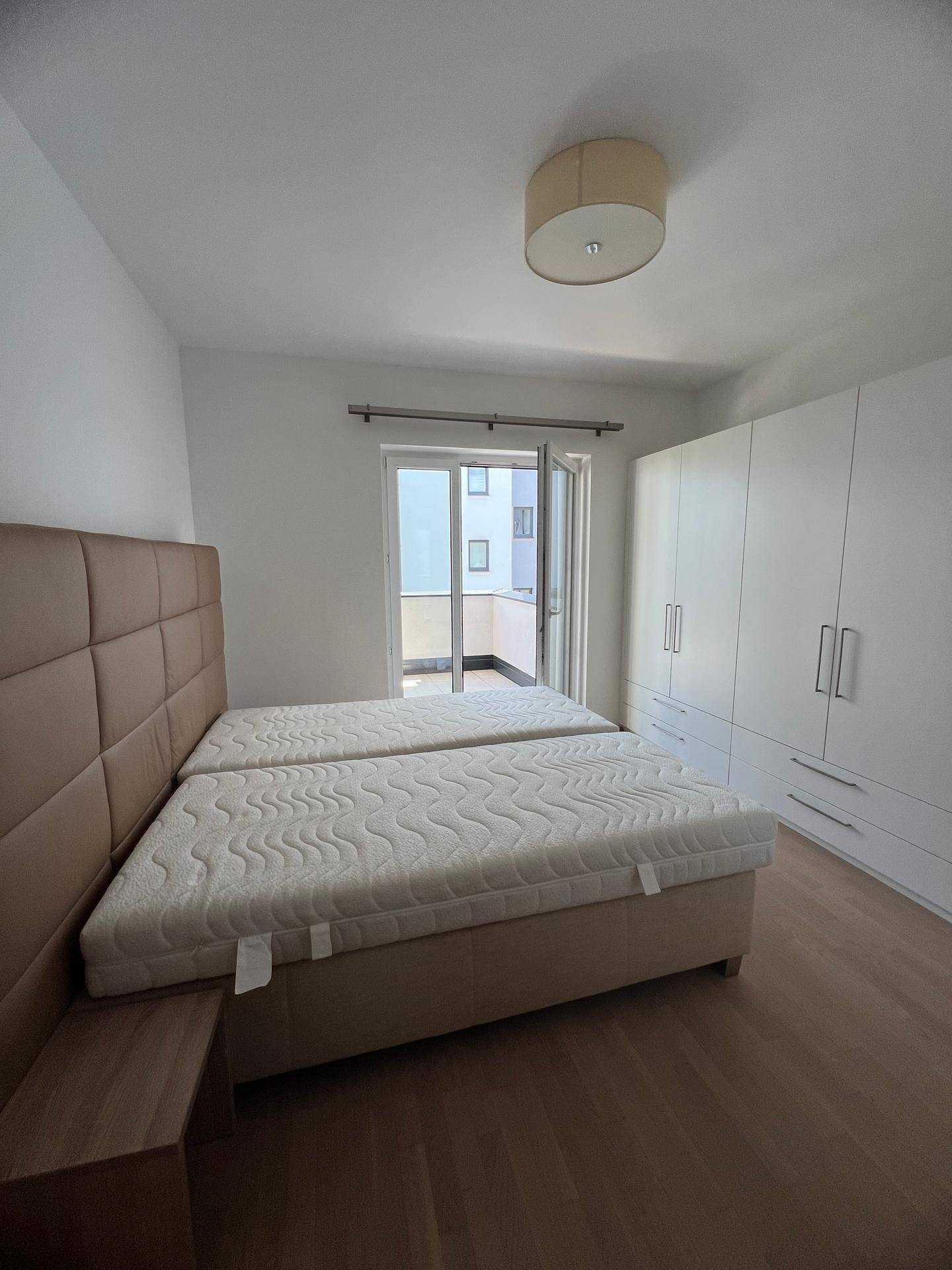 Helles Schlafzimmer mit Doppelbett, großem Kleiderschrank und Balkonzugang.