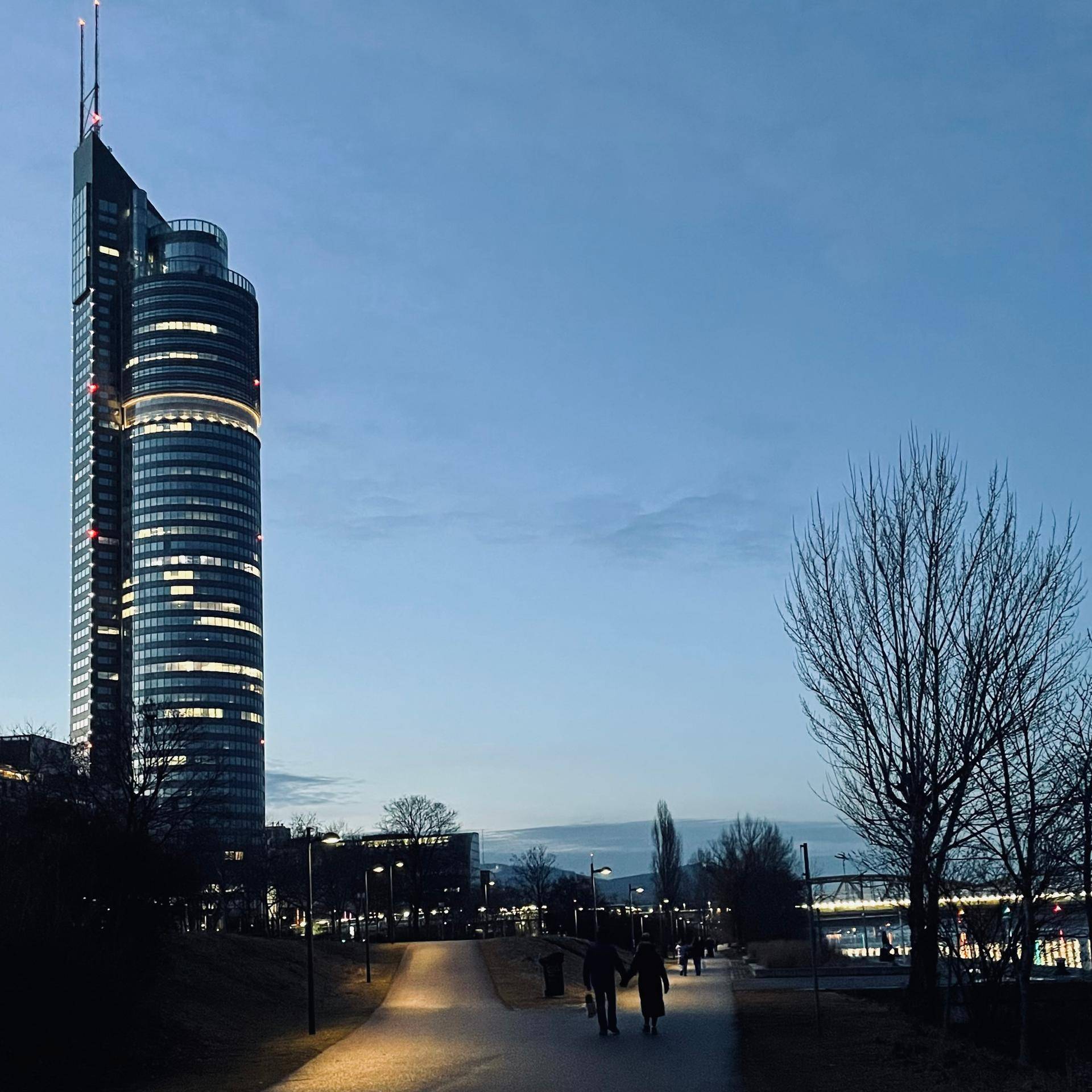 Moderne Hochhäuser in einer Stadtlandschaft bei Dämmerung mit beleuchteten Fenstern und einem klaren Himmel.
