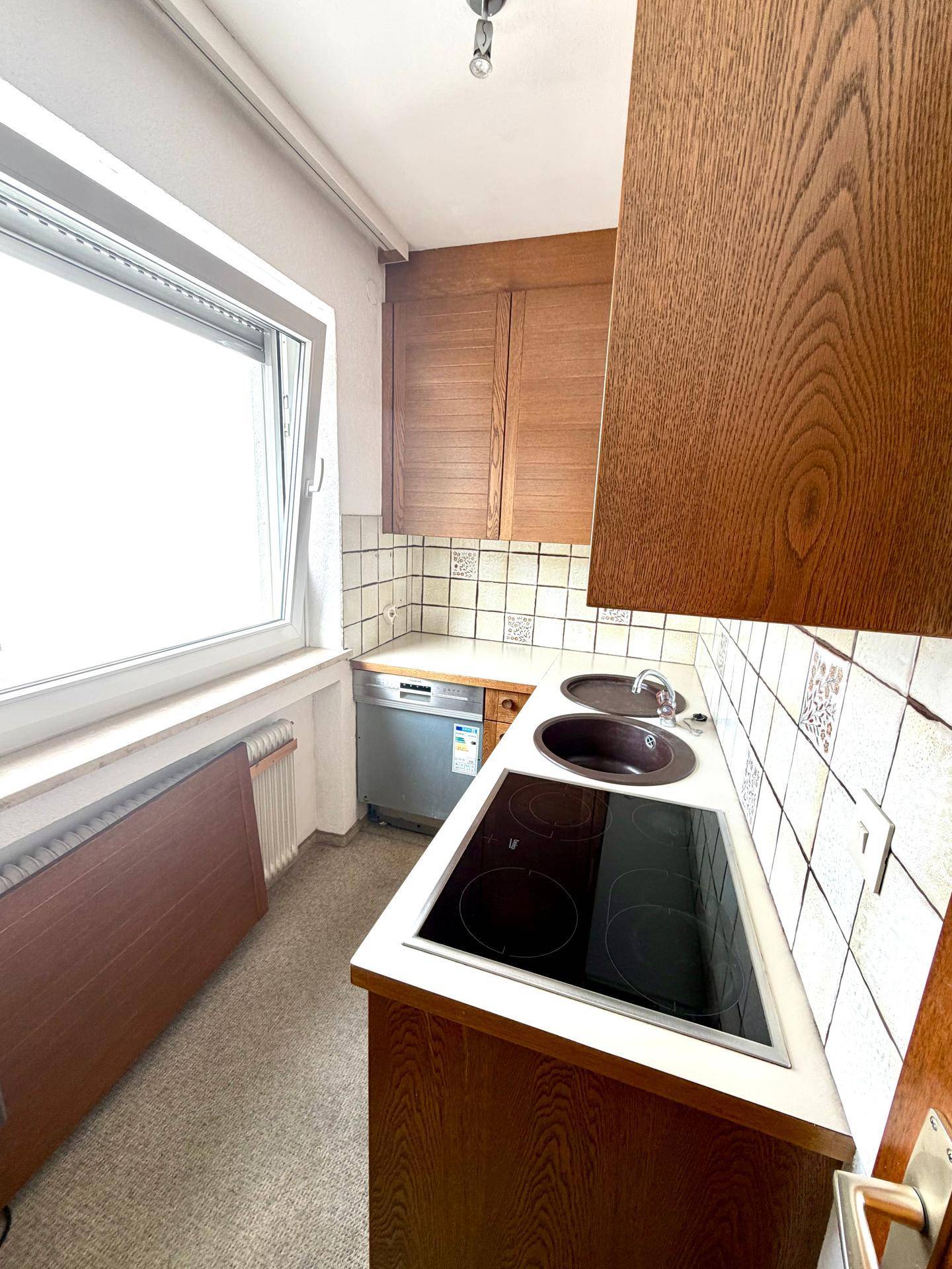 Funktionale Küche mit Holzfronten, Spülbecken und integriertem Induktionskochfeld.