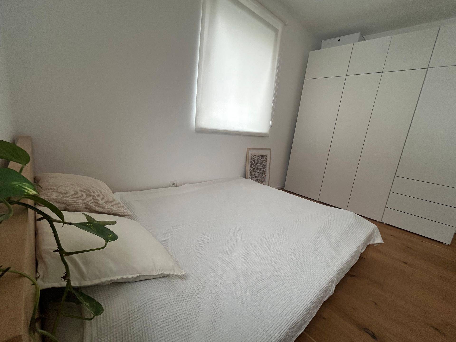 Helles Schlafzimmer mit einem großen Bett, weißem Kleiderschrank und Holzboden.