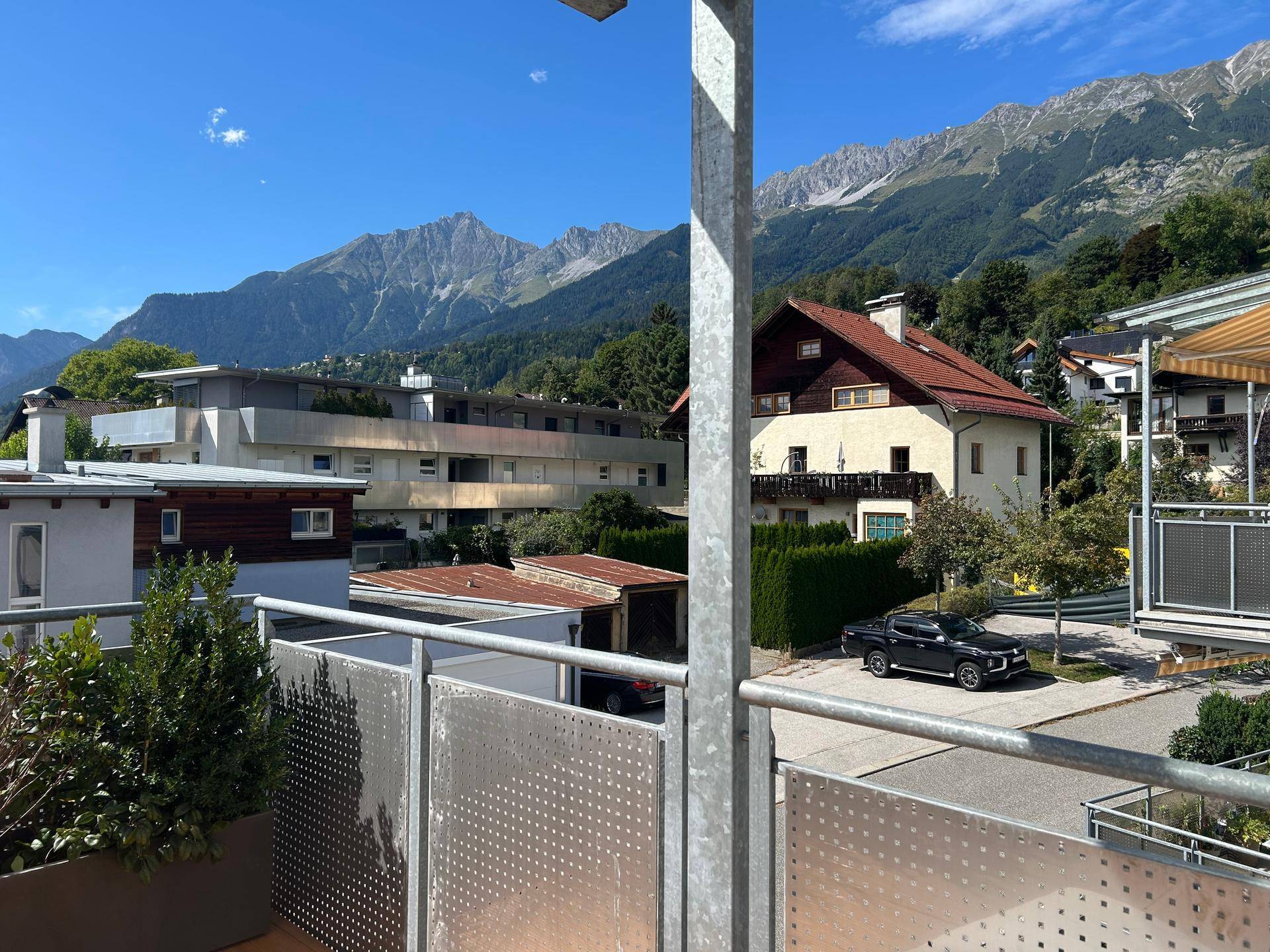 Panoramablick von einem Balkon auf die umliegende Wohngegend und die majestätischen Berge.