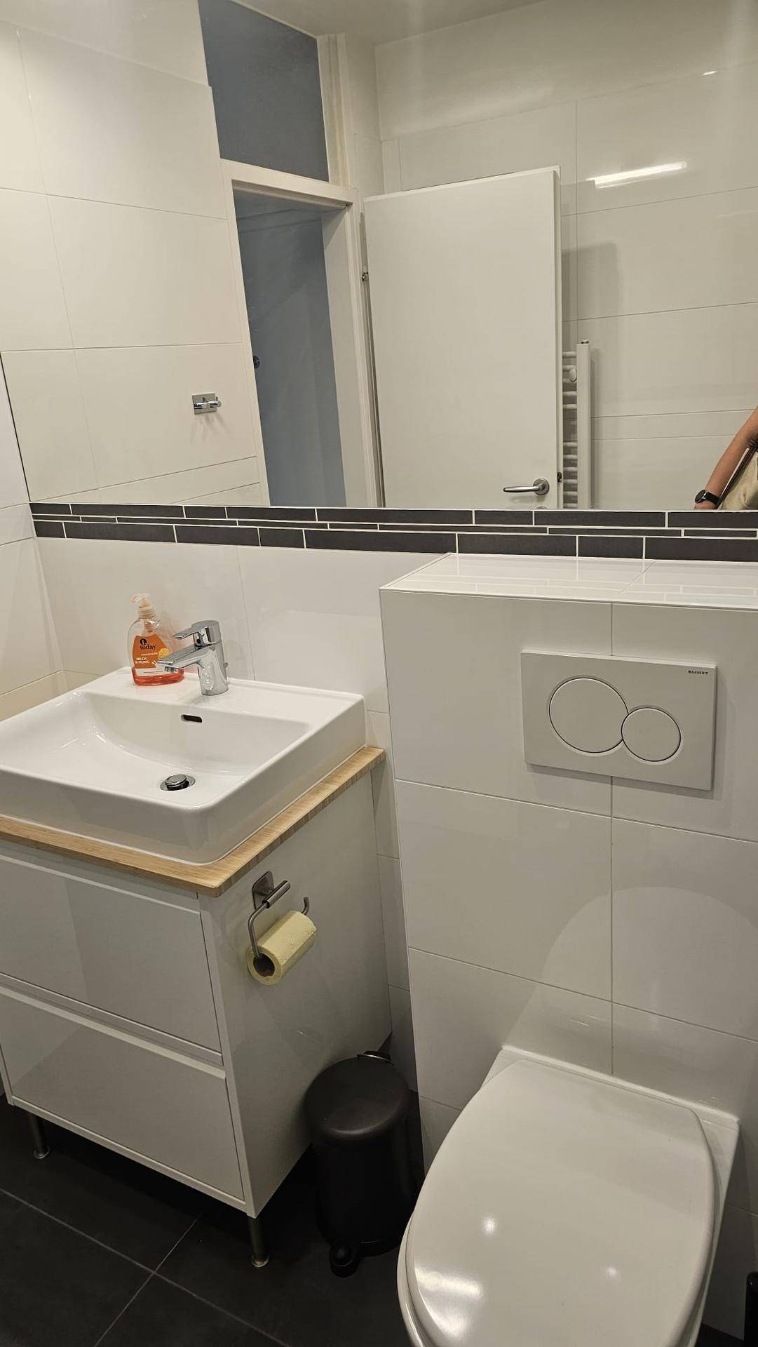 Helles Badezimmer mit modernem Waschtisch, wandhängendem WC und großem Spiegel.