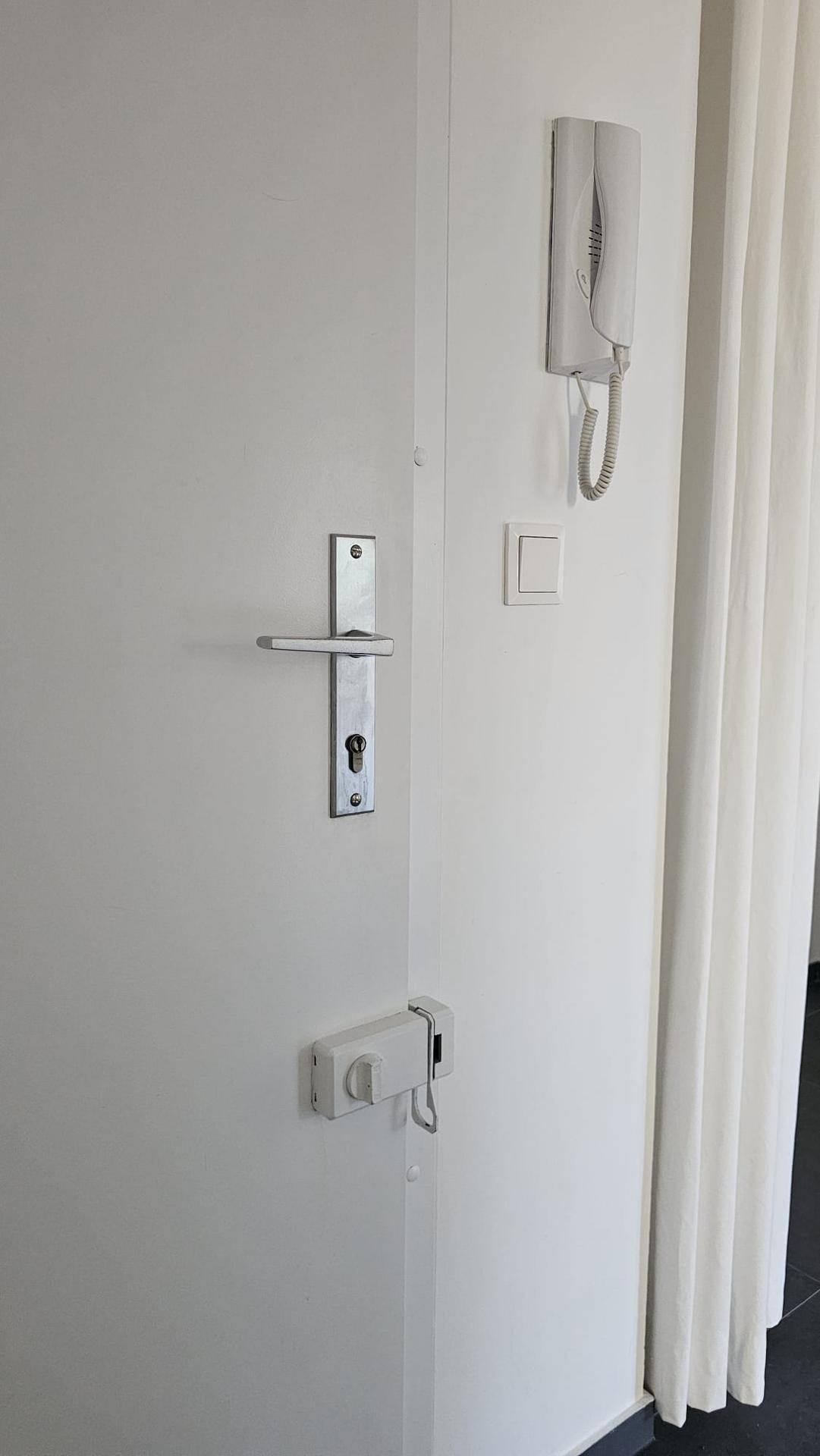 Eingangstür einer Wohnung mit Gegensprechanlage und modernem Türgriff.