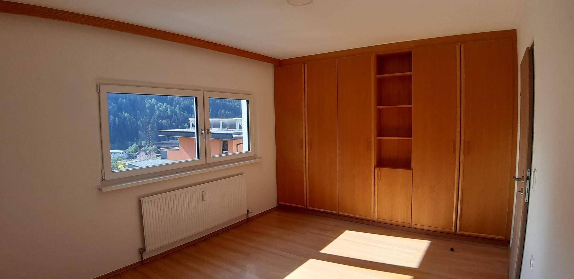 Schlafzimmer mit Einbauschränken, Holzboden und Fenster mit Blick auf die Berge.
