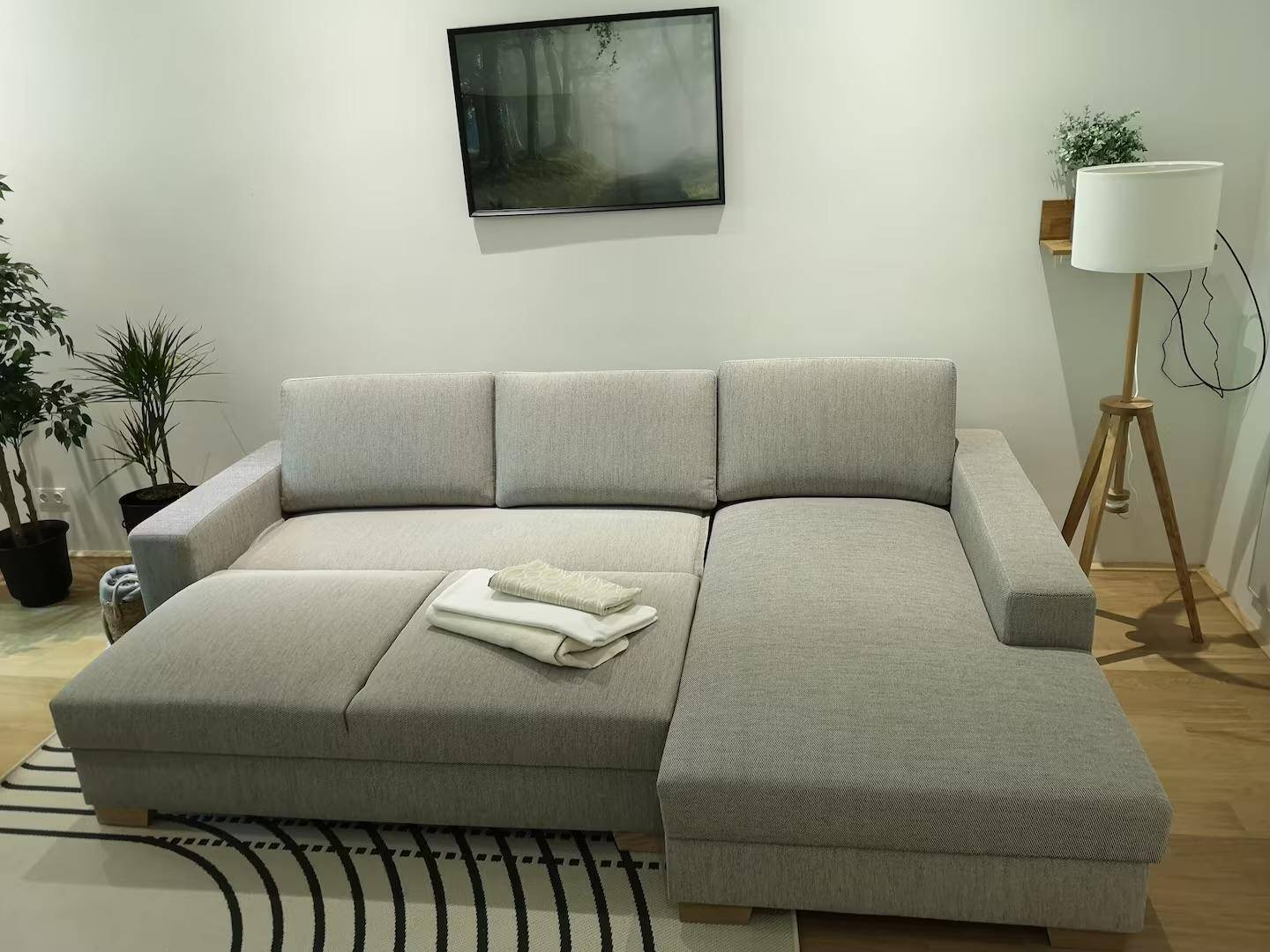 Großes, bequemes Ecksofa im Wohnzimmer mit Decke und Kissen.