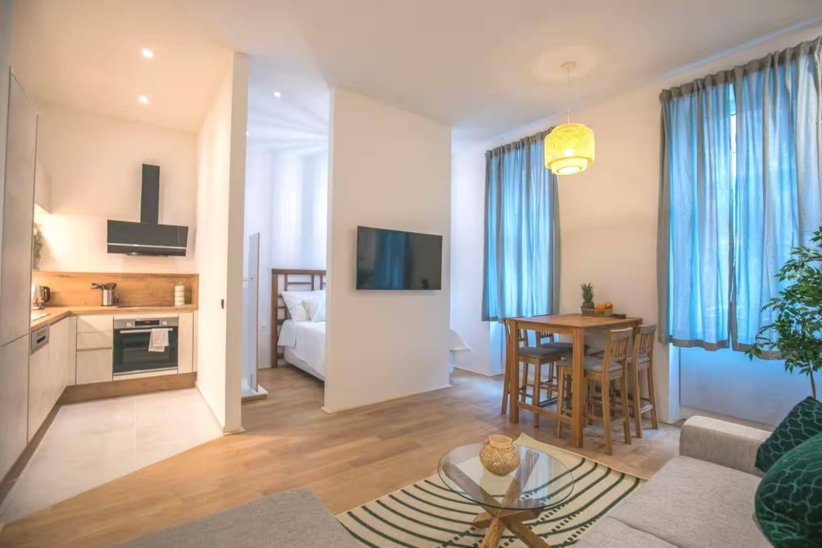 Offener Wohnbereich mit integrierter Küche, Essbereich und Zugang zum Schlafzimmer.