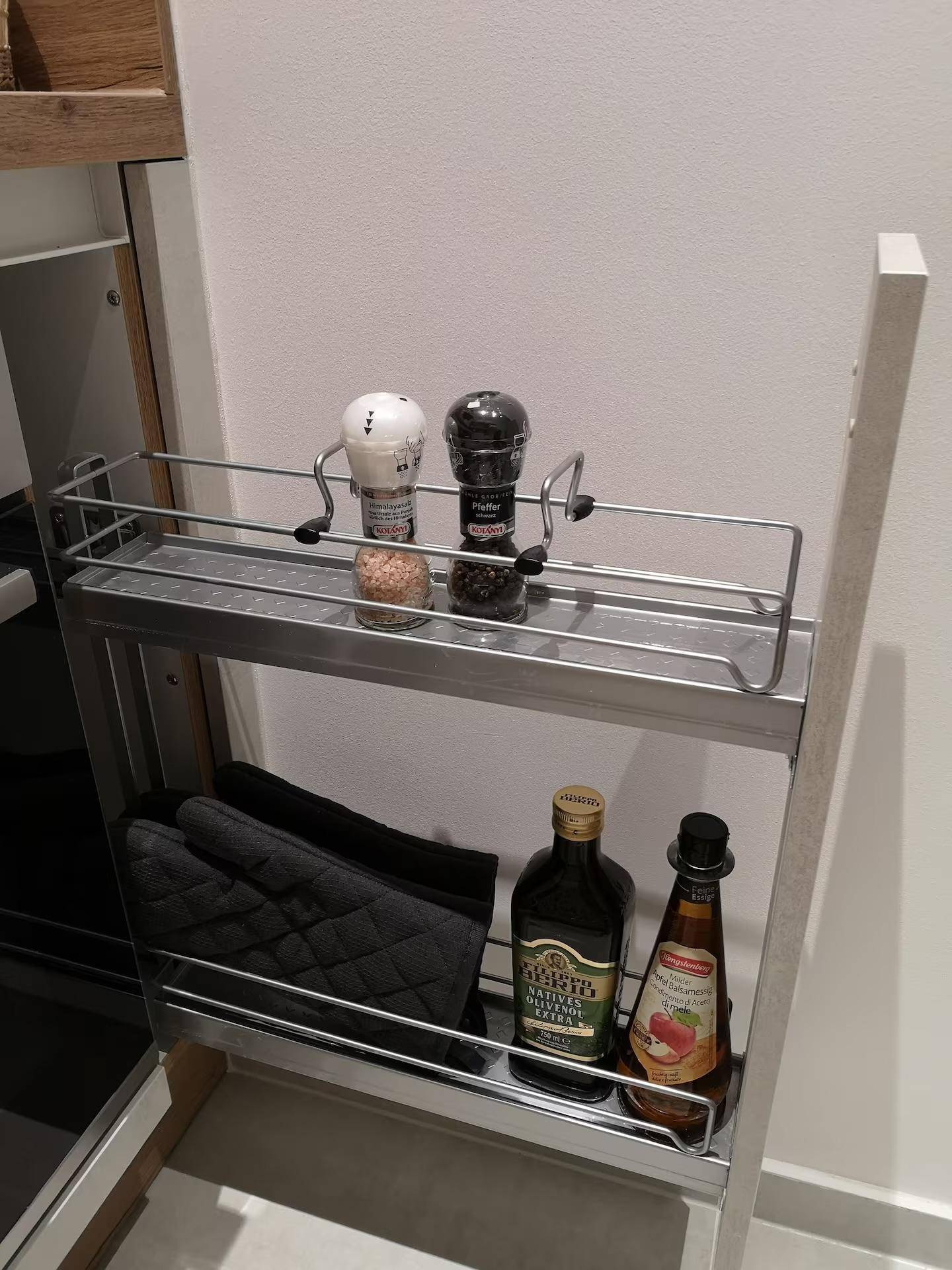 Ausziehbarer Gewürzschrank in der Küche mit verschiedenen Gewürzen und Flaschen.