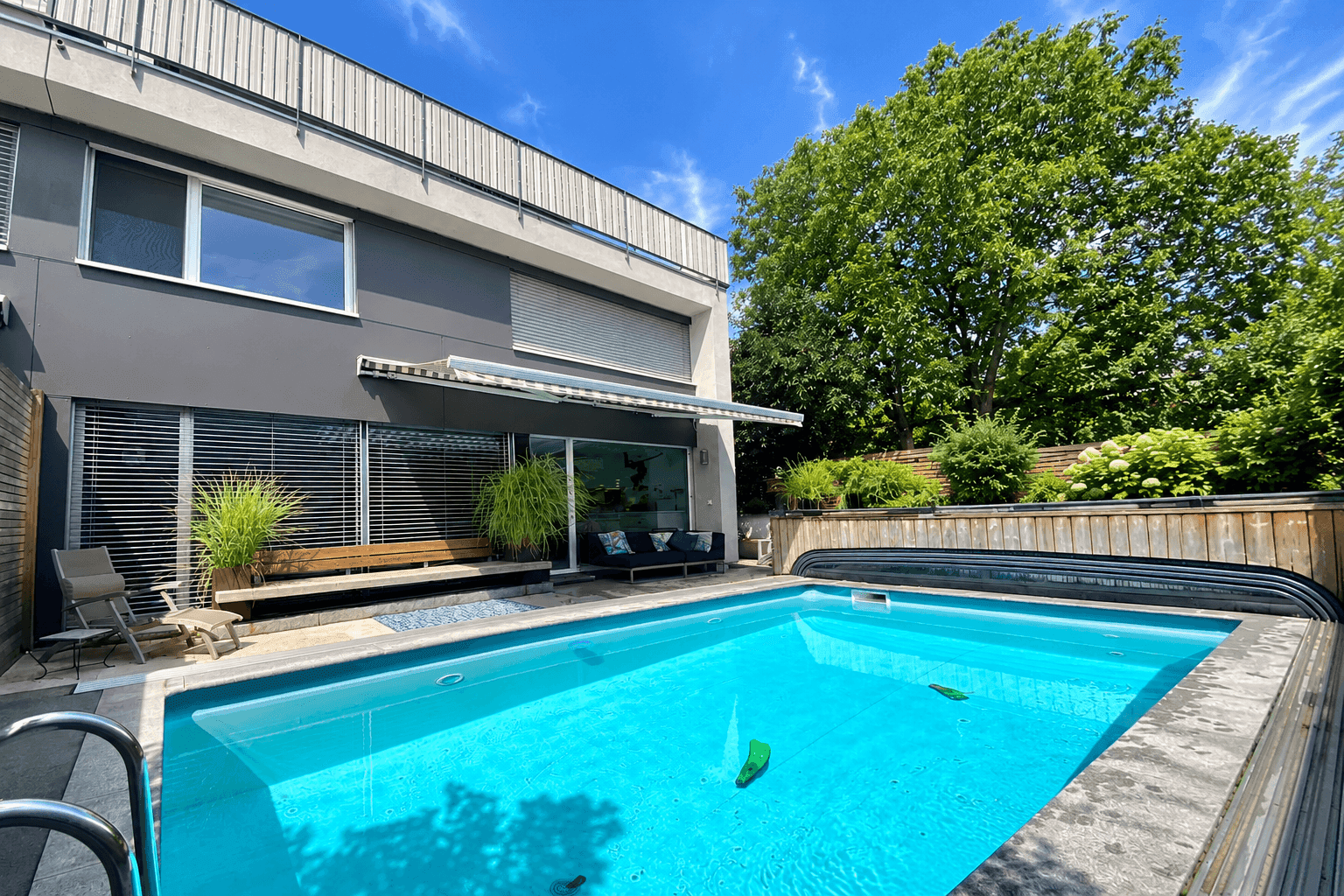 Modernes Haus mit privatem Swimmingpool im Garten und üppiger Grünanlage.