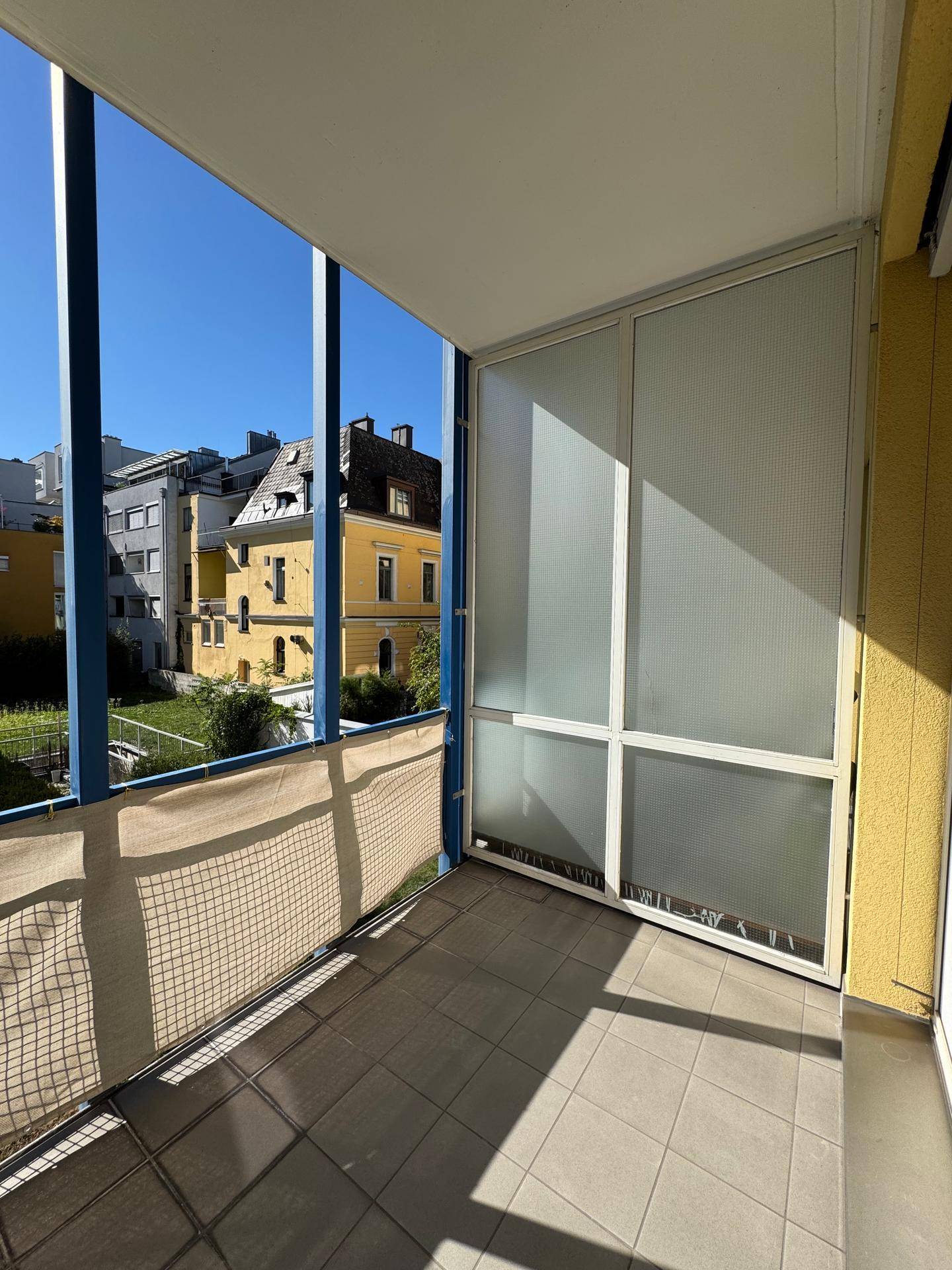 Geräumiger Balkon mit Fliesenboden und Blick auf die Nachbarschaft, ideal zum Entspannen.