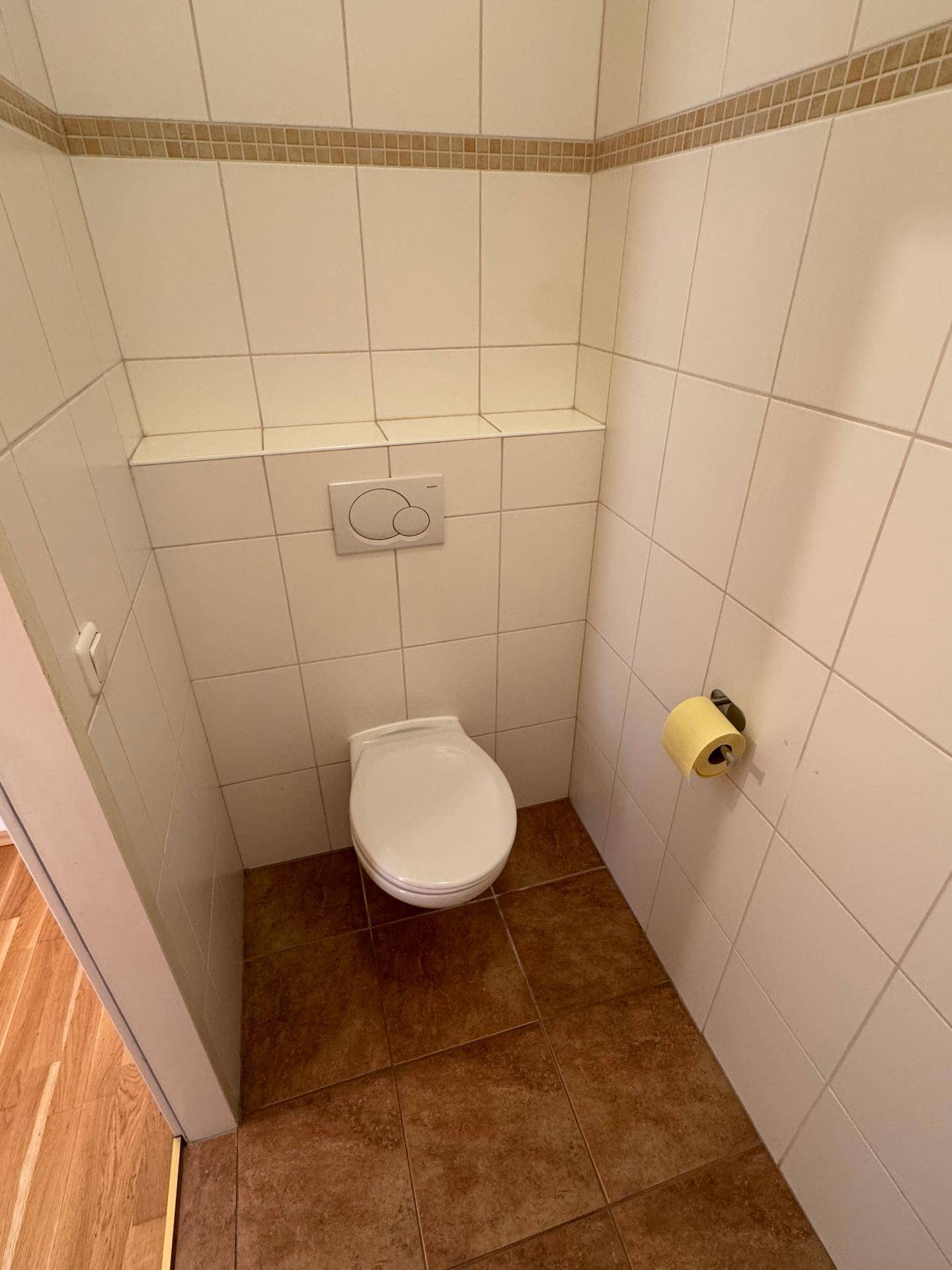 Separates WC mit Wand-WC und hellen Fliesen, funktional und sauber gestaltet.