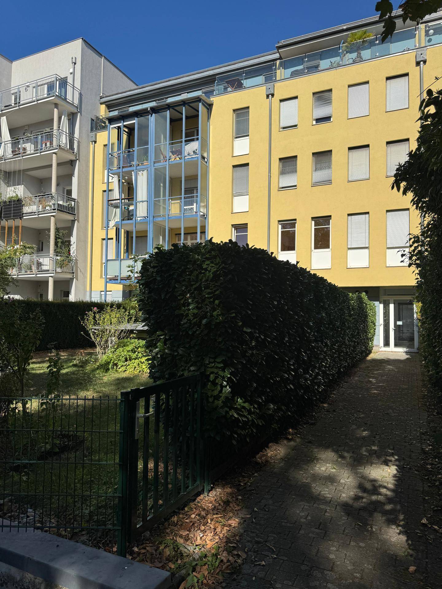Moderne Wohnanlage mit gelber Fassade und gepflegter Grünfläche im Vordergrund.
