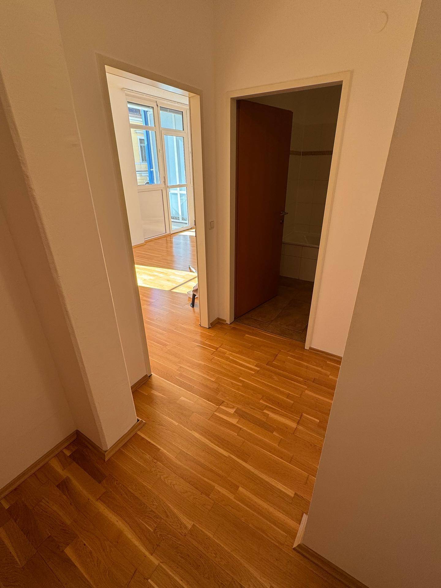 Heller Flur mit Parkettboden, der zu weiteren Zimmern und dem Balkon führt.