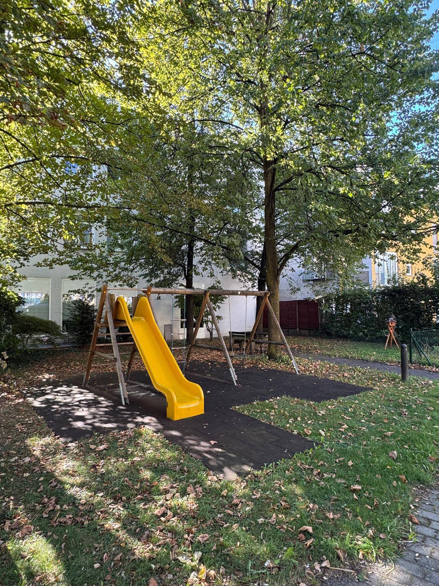 Kinderspielplatz mit Rutsche und Schaukeln in einer grünen Umgebung, ideal für Familien.