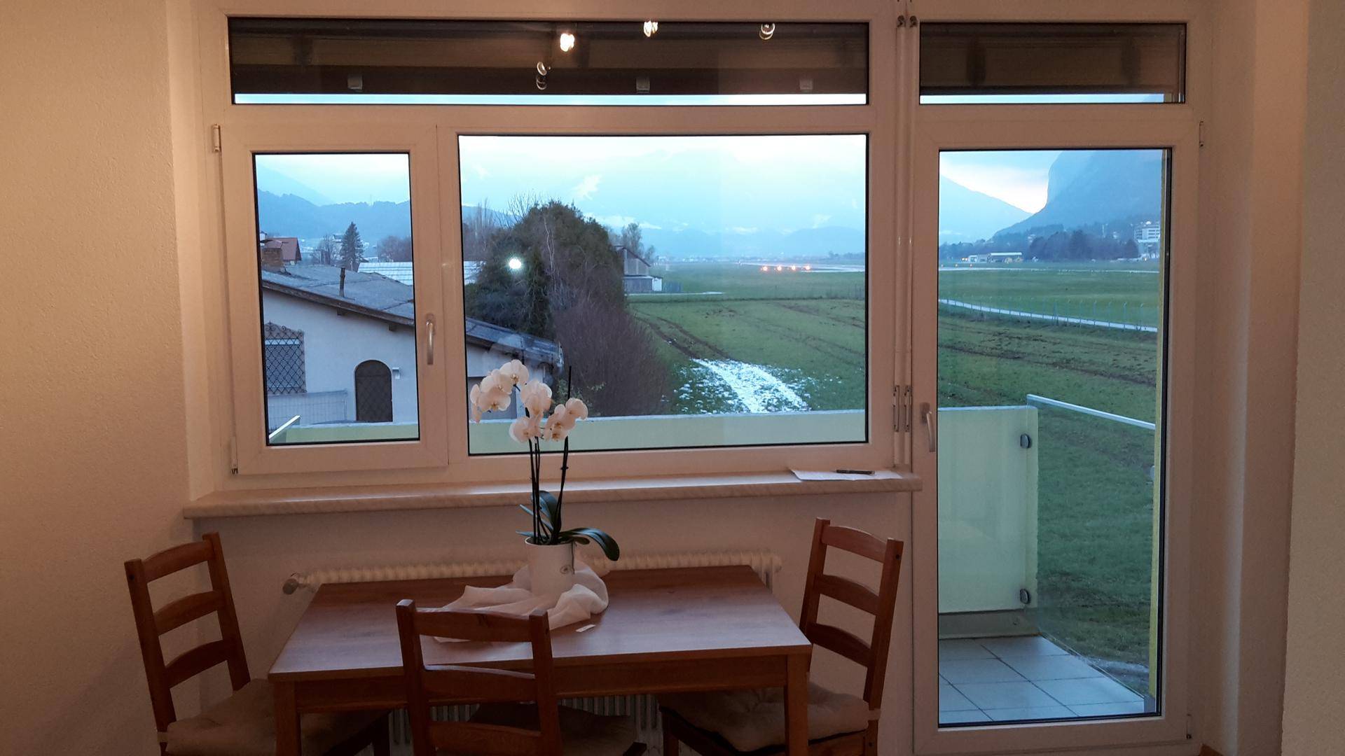 Gemütlicher Essbereich mit Holztisch, Balkonzugang und Bergblick.