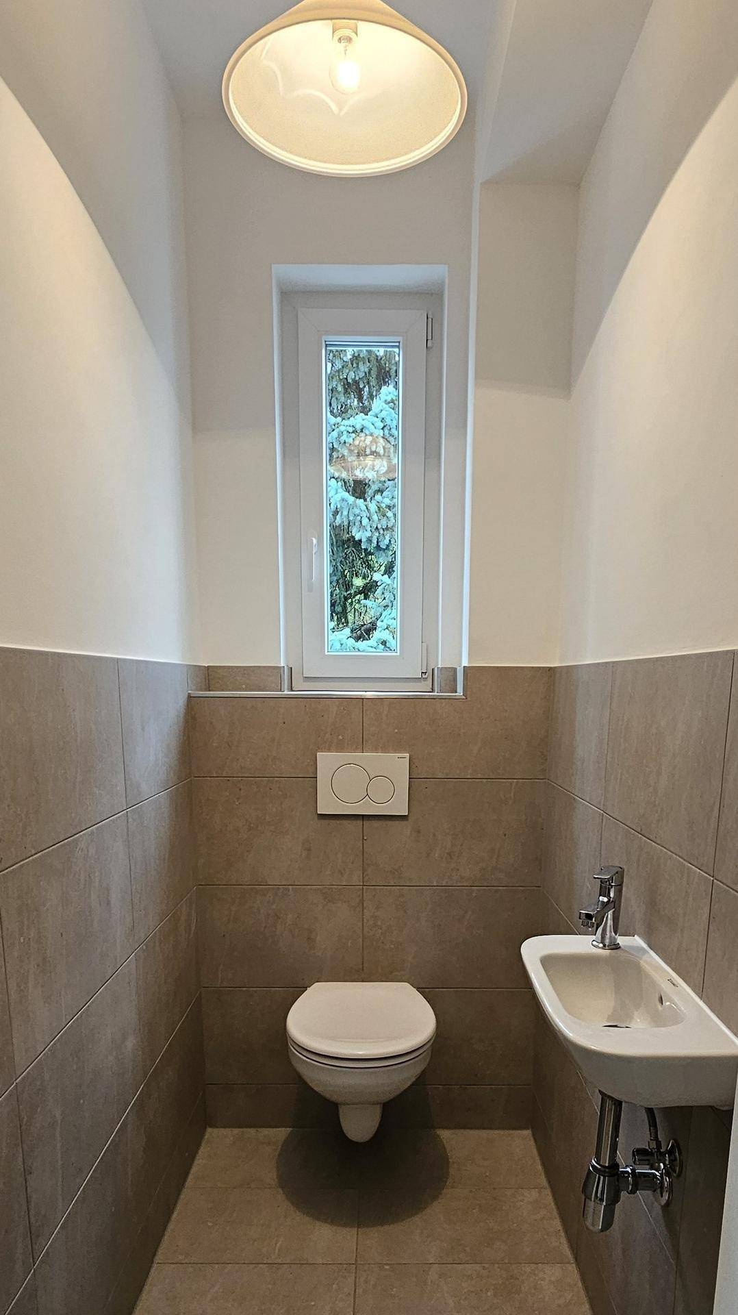 Kleines Gäste-WC mit Fenster, Wand-WC und einem Bidet, ausgestattet mit Fliesen.