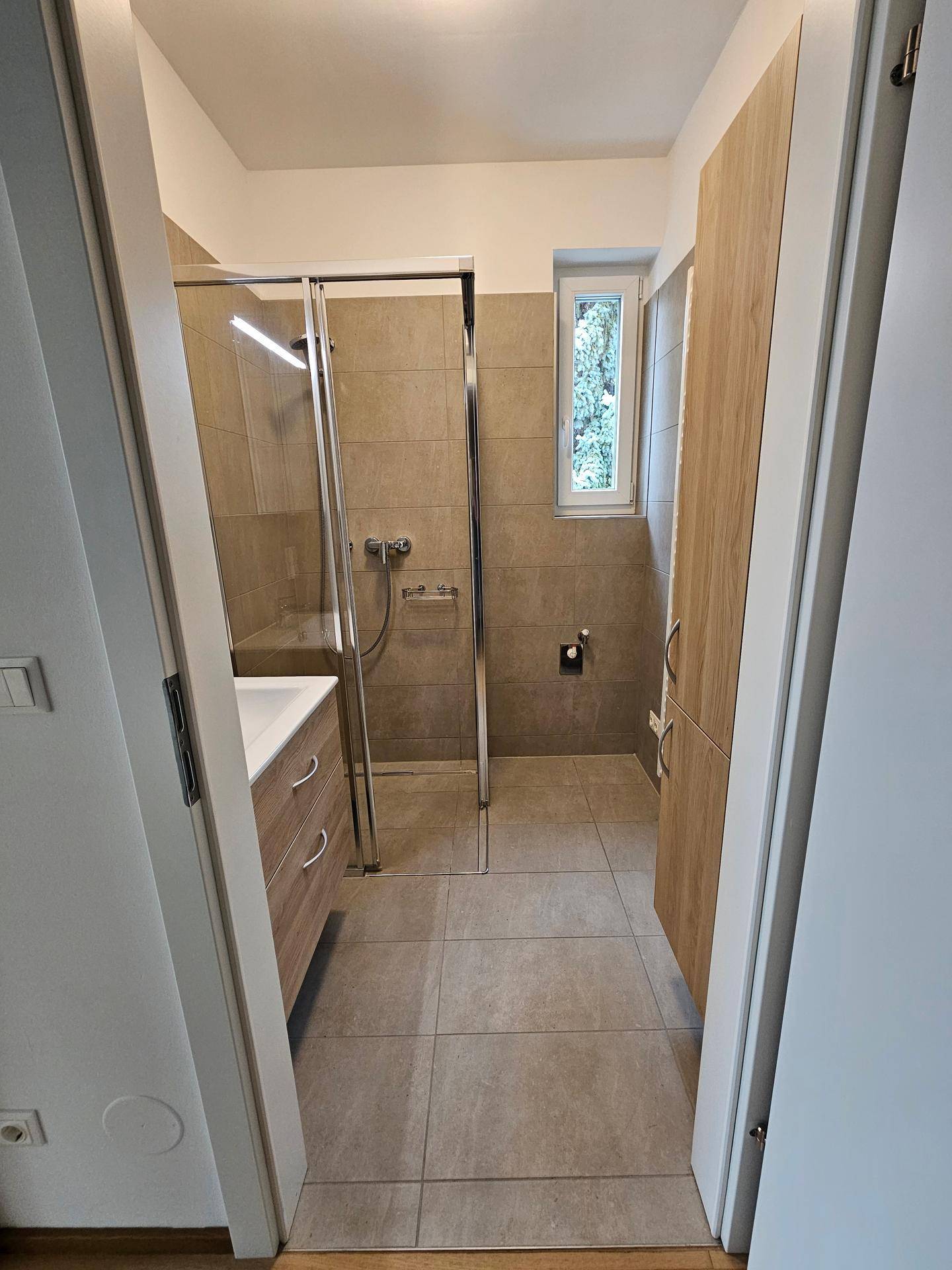 Modernes Badezimmer mit begehbarer Dusche, Waschtisch und Fenster für natürliches Tageslicht.