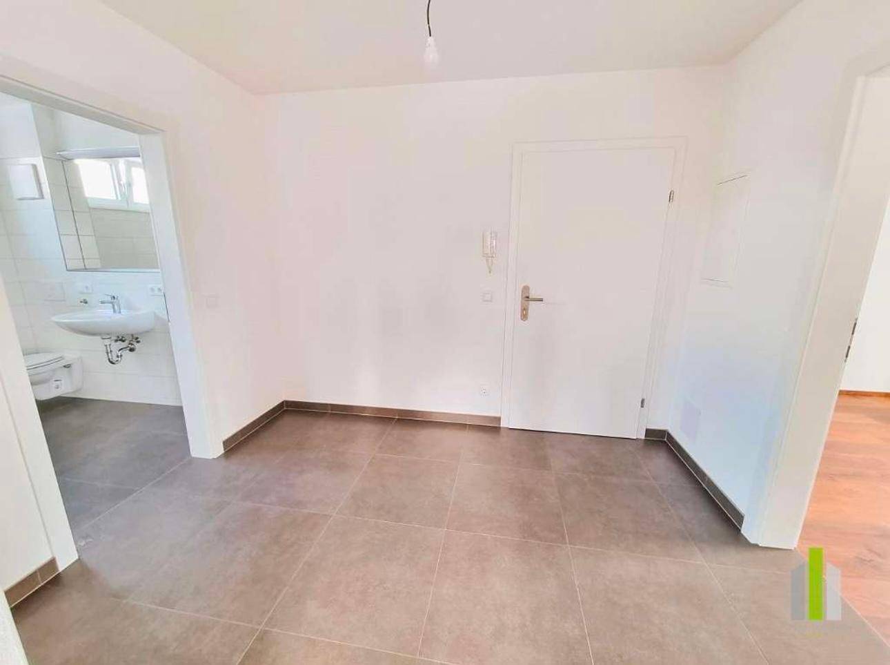 Eingangsbereich mit Fliesenboden und Zugang zu einem Badezimmer, hell und funktional gestaltet.