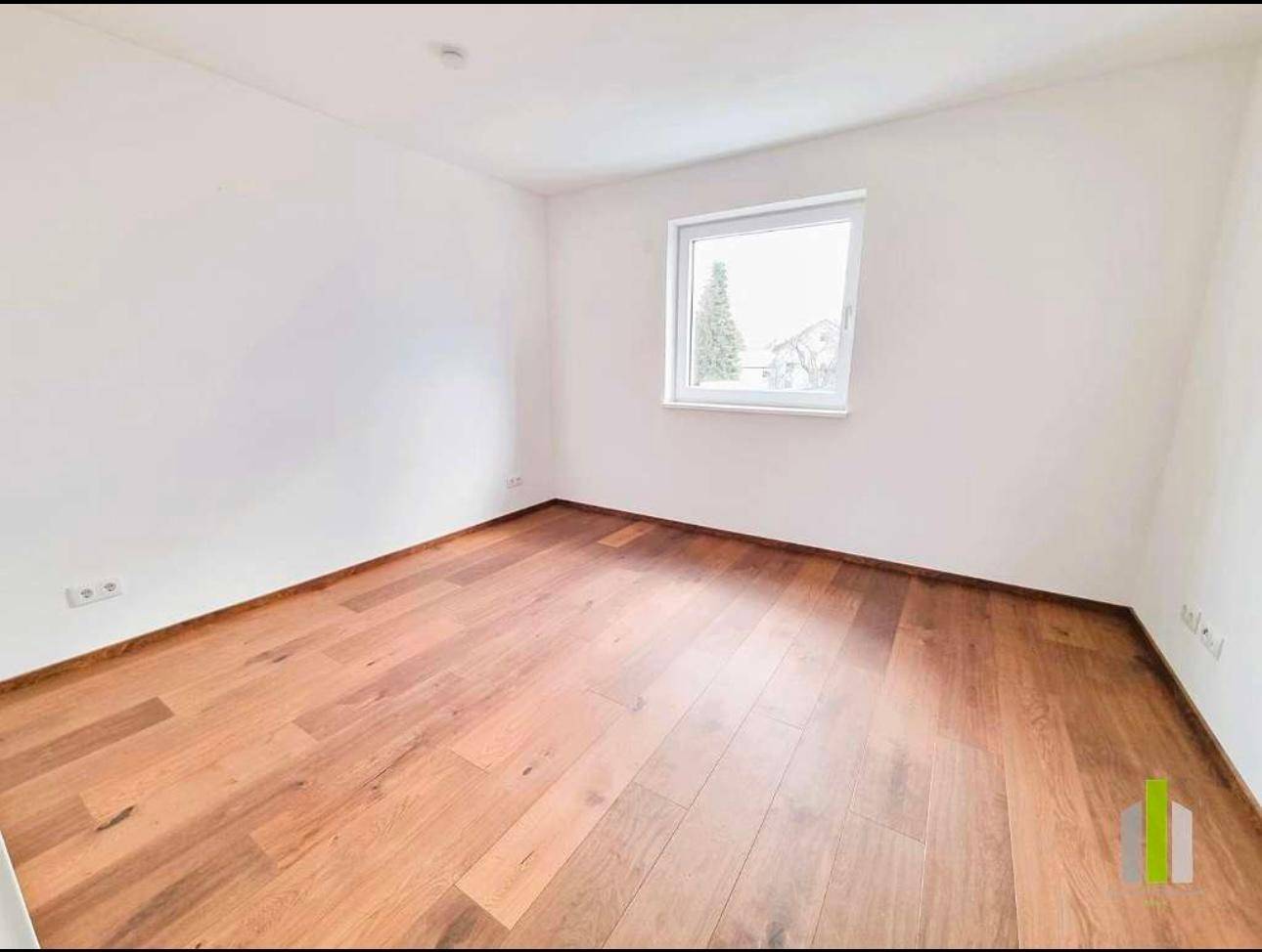 Ruhiges Schlafzimmer mit Holzboden und einem Fenster, das eine angenehme Atmosphäre schafft.