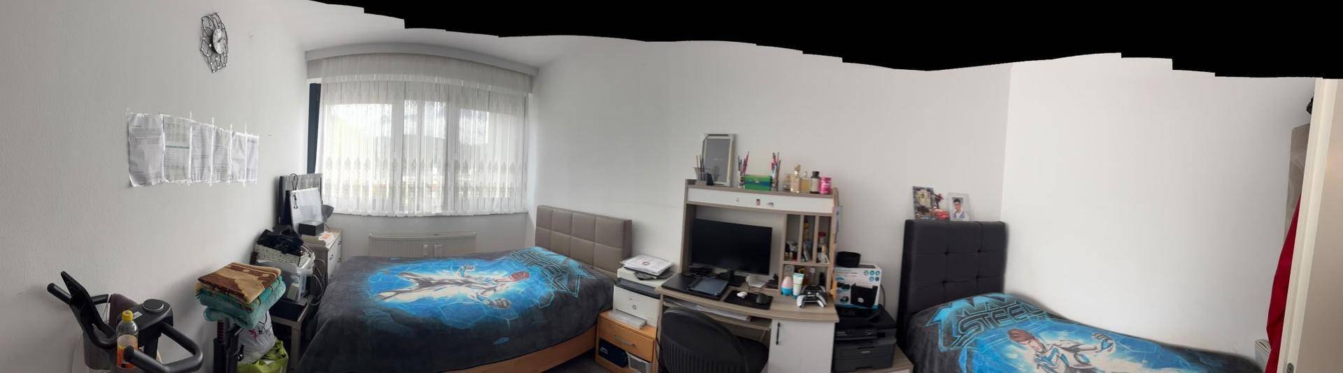Helles Schlafzimmer mit zwei Betten, Schreibtisch und großem Fenster für viel Tageslicht.
