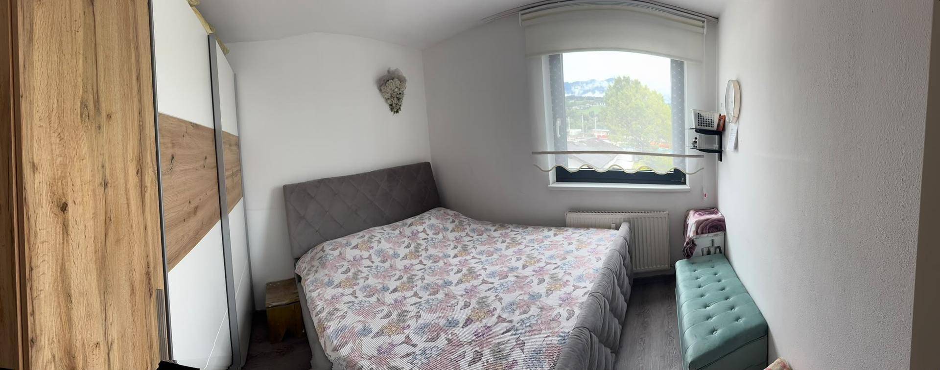 Gemütliches Schlafzimmer mit Doppelbett, modernem Kleiderschrank und Fenster mit Ausblick.
