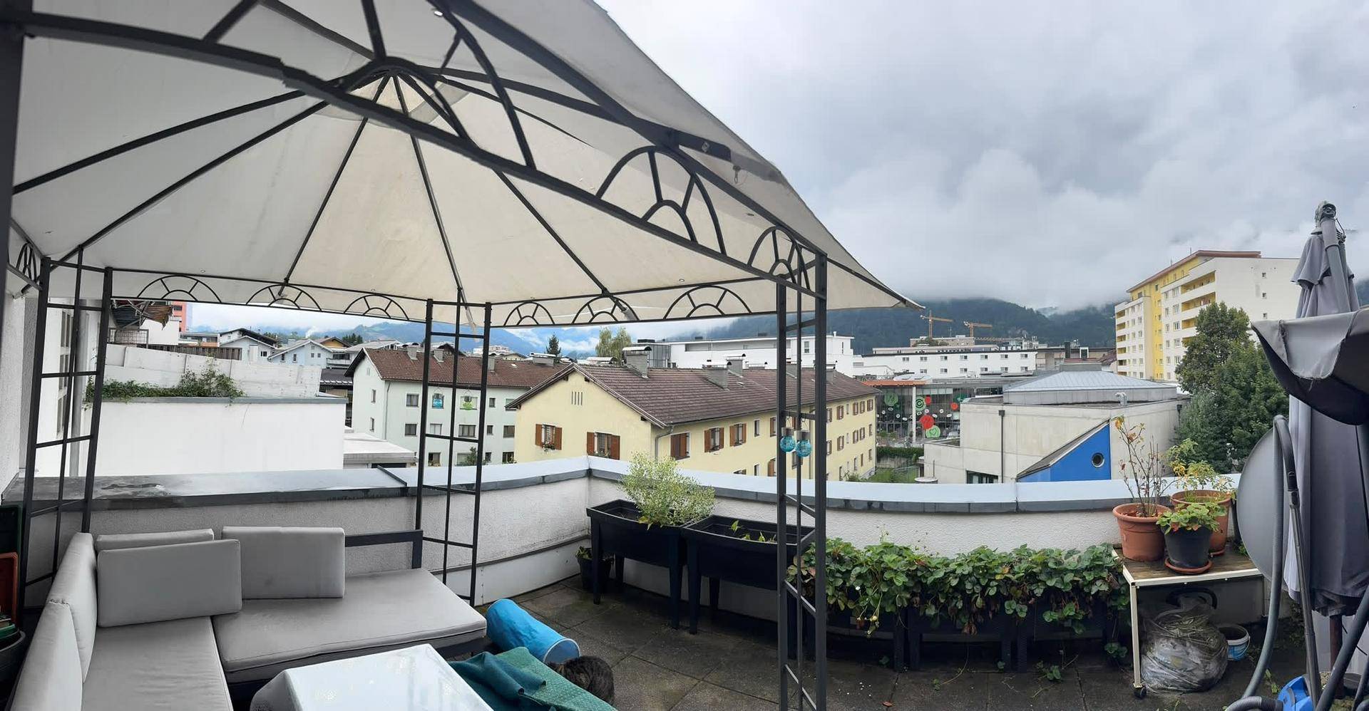 Geräumige Dachterrasse mit Pavillon, Sitzgelegenheiten und weitem Blick über die Stadt und Berge.
