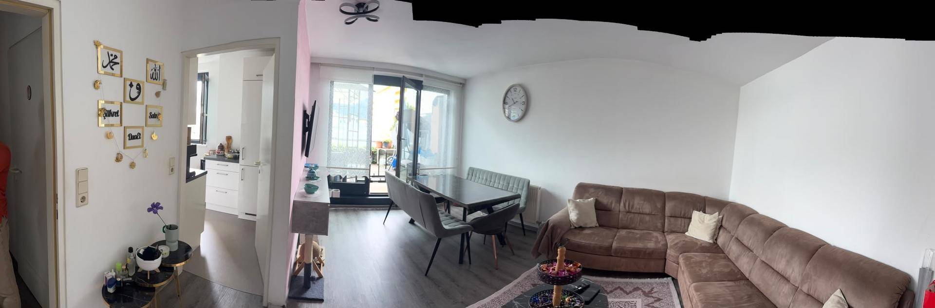 Geräumiger Wohn-Essbereich mit bequemer Couch, Esstisch und Zugang zu einem Außenbereich.