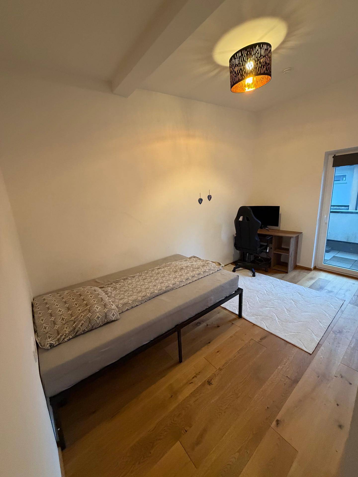 Helles Zimmer mit Holzboden, Einzelbett und Schreibtisch, ideal als Gästezimmer.