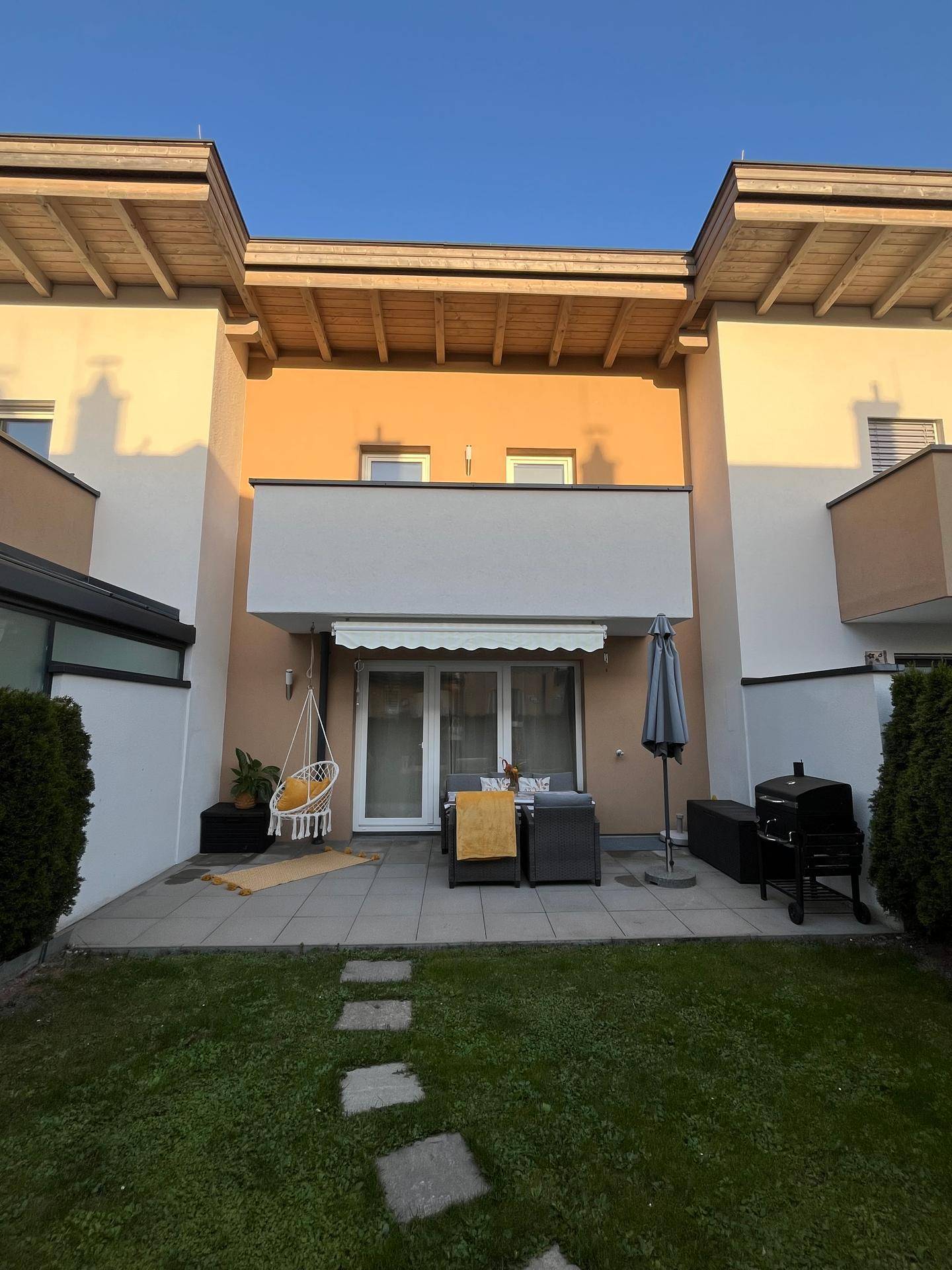 Gepflegter Garten mit Rasenfläche, Terrasse und Grillbereich hinter dem Haus.