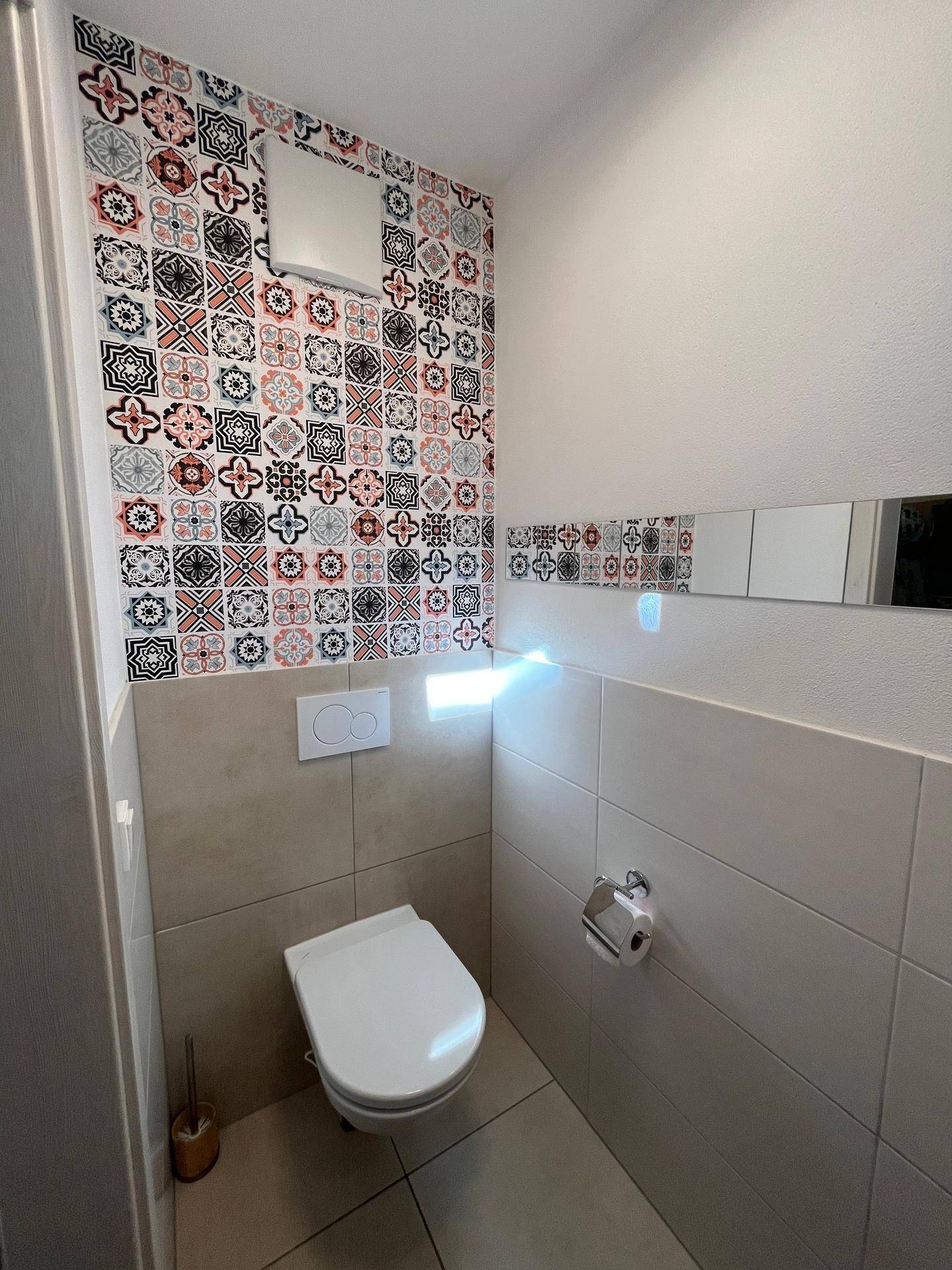 Gäste-WC mit farbenfroher Tapete, Wand-WC und modernen Fliesen.