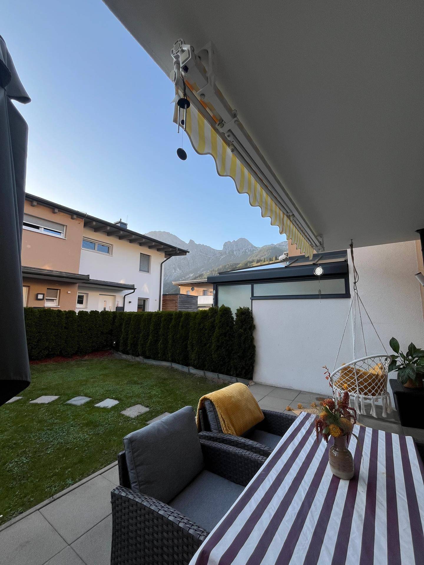 Gemütliche Terrasse mit Gartenmöbeln, Markise und Blick auf die Berge.