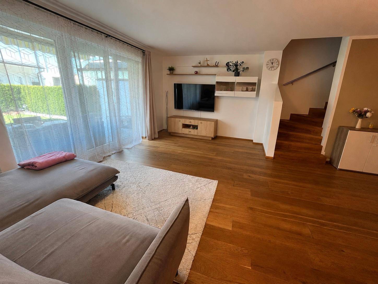 Geräumiges Wohnzimmer mit Holzboden, großem Sofa und Zugang zur Terrasse.