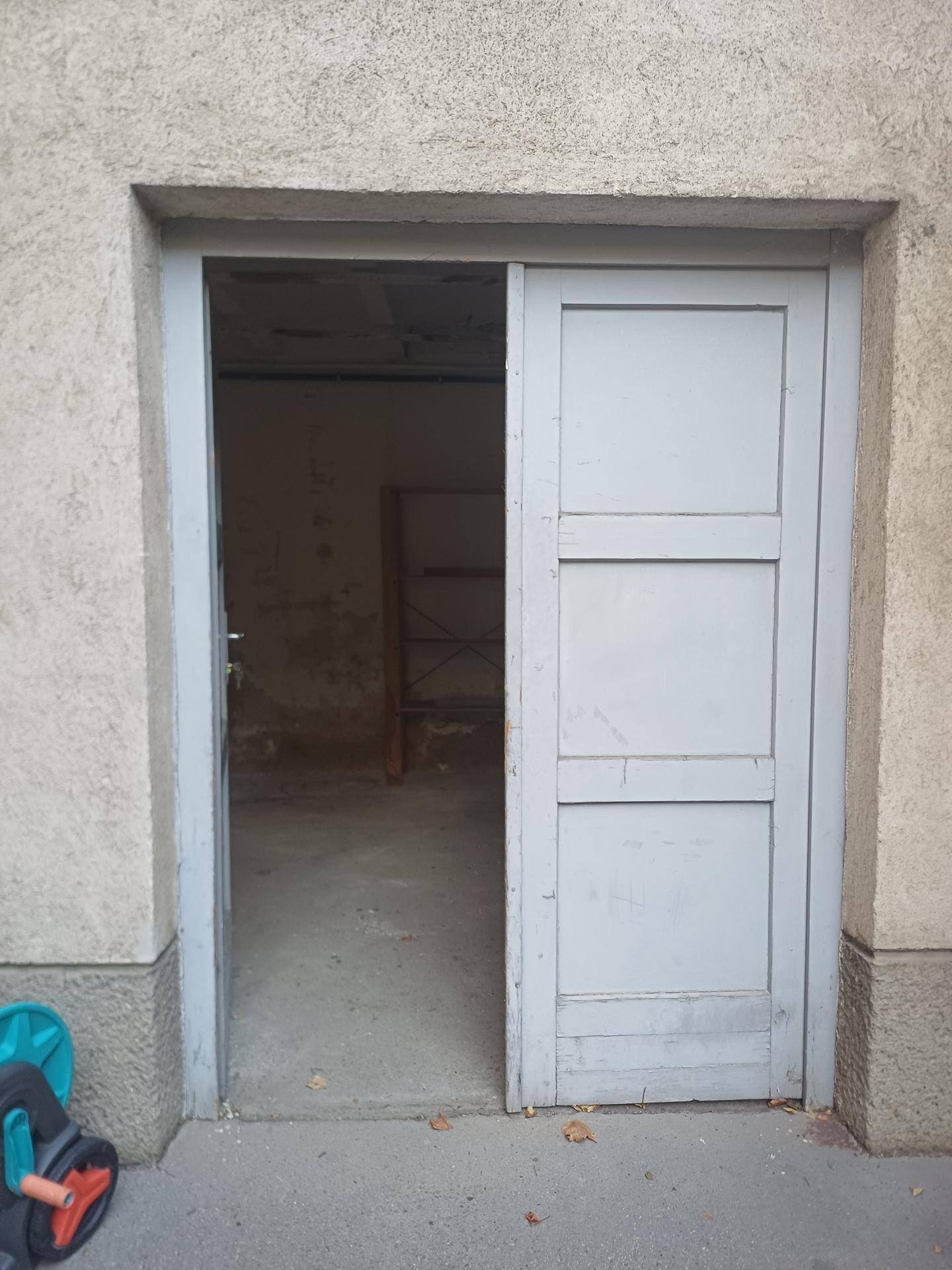 Offene graue Doppeltür, die den Blick in einen einfachen Kellerraum freigibt.