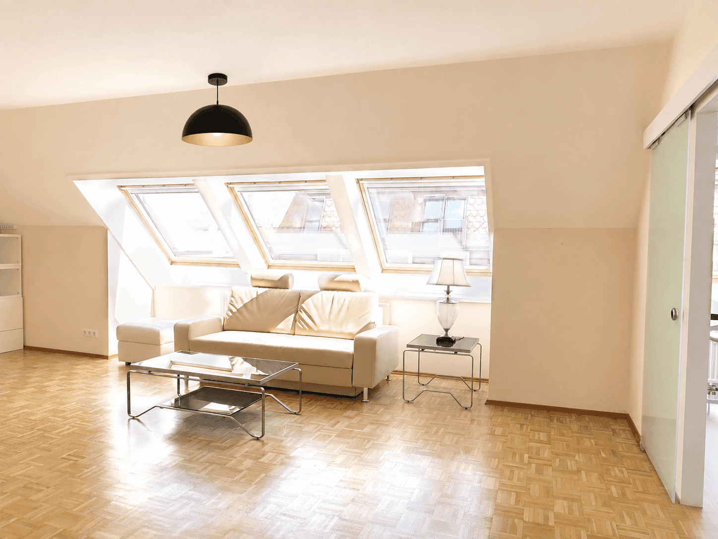 Helles Wohnzimmer im Dachgeschoss mit Schrägdach, Dachfenstern und hellem Parkettboden.