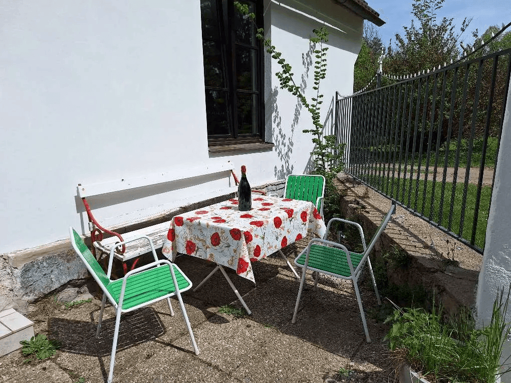 Gemütliche Terrasse mit Gartentisch und Stühlen vor der weißen Hausfassade.