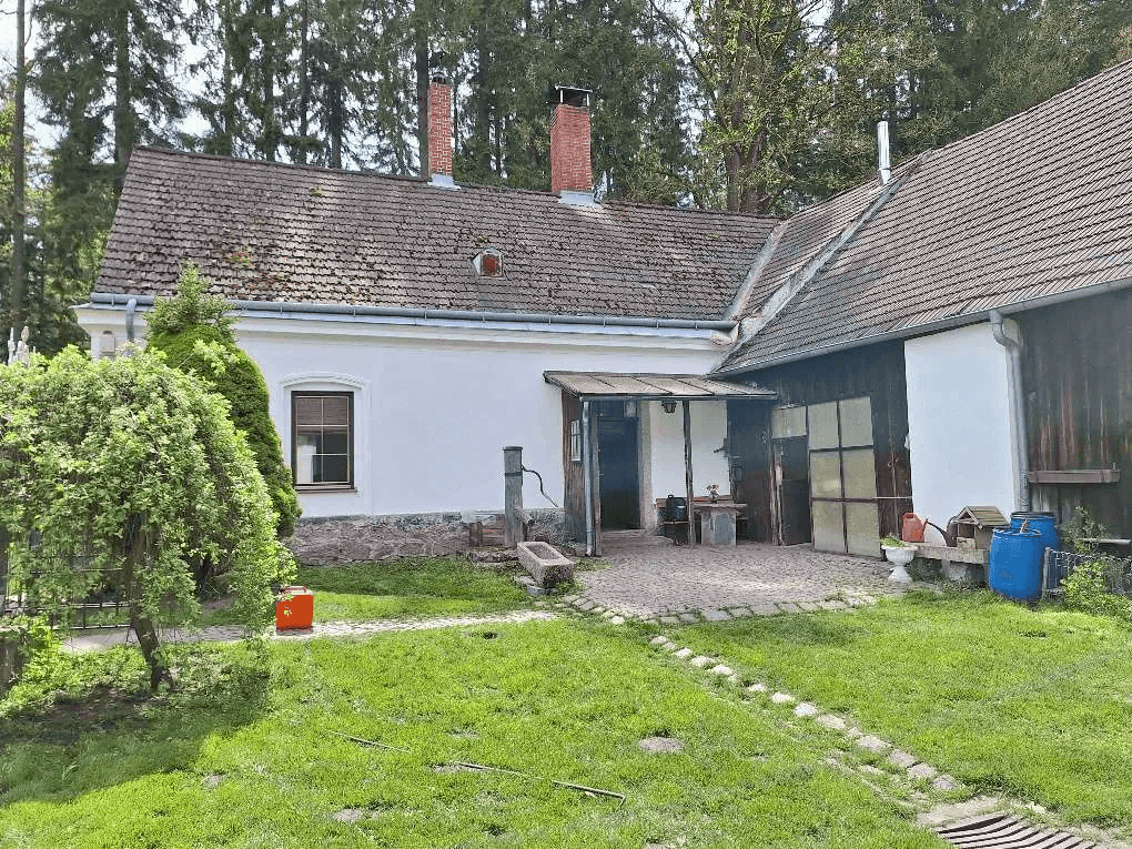 Rückseite eines Landhauses mit überdachtem Eingangsbereich und ländlichem Charme.