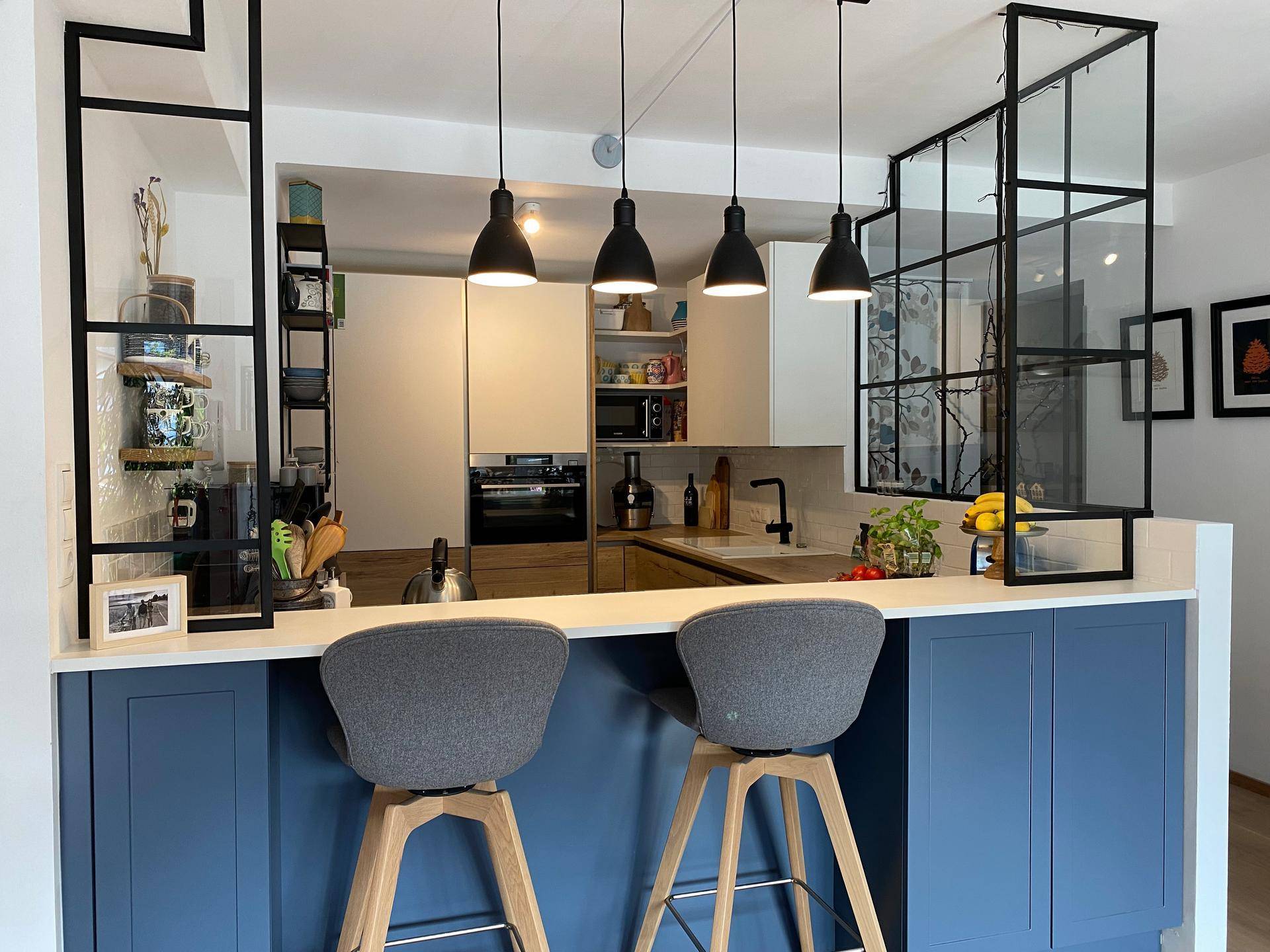 Moderne Küche mit Kücheninsel, blauen Unterschränken und schwarzen Pendelleuchten.