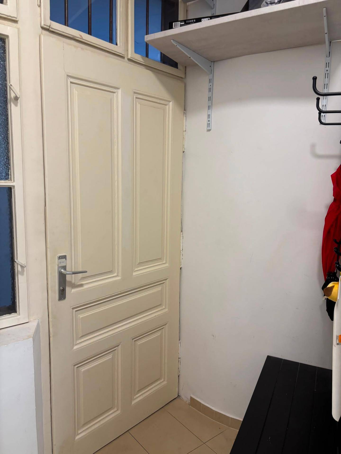 Eingangsbereich mit heller Tür, Fenster und praktischen Wandregalen für Stauraum.