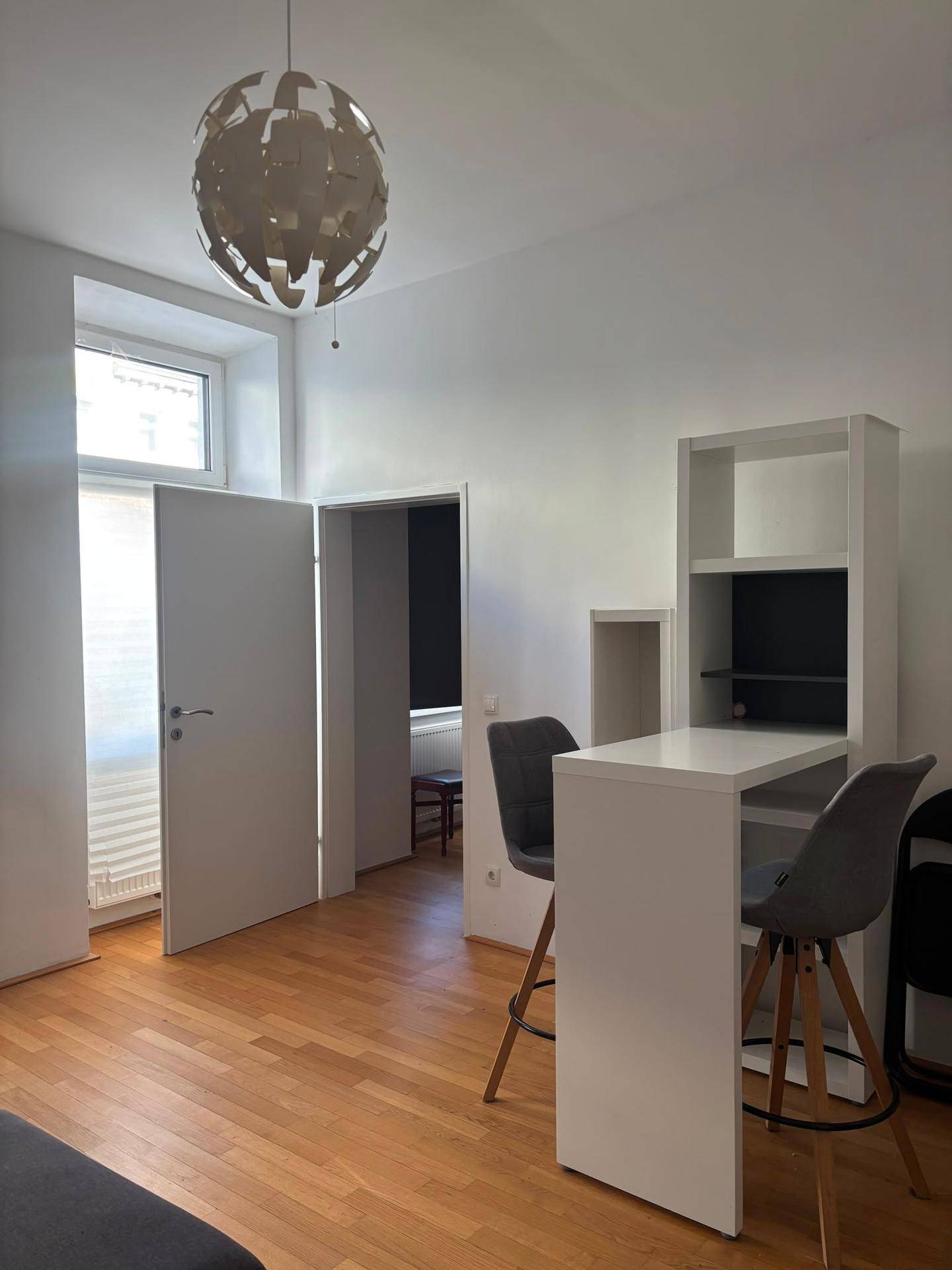 Heller Wohnbereich mit modernem Bartisch, Stühlen und Zugang zu einem weiteren Raum.