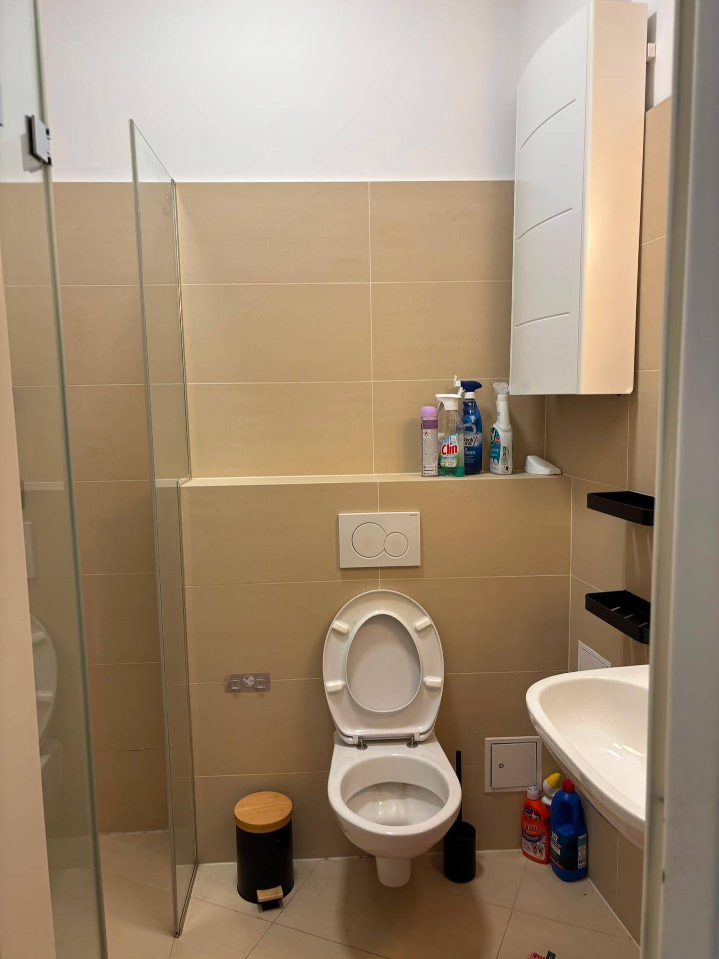 Modernes Badezimmer mit beigen Fliesen, wandhängendem WC und kleiner Waschtisch.