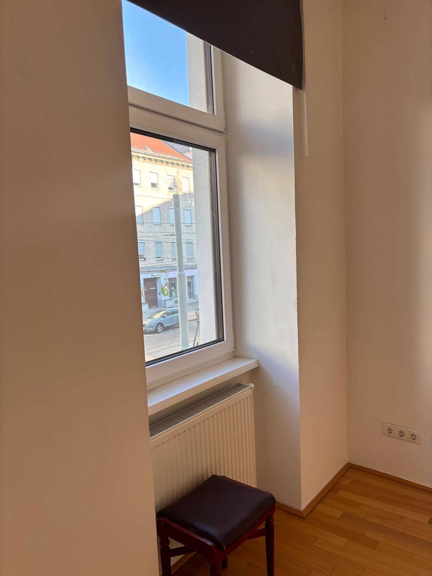 Fenster mit Blick auf die Straße und Heizkörper darunter in einem hellen Raum.