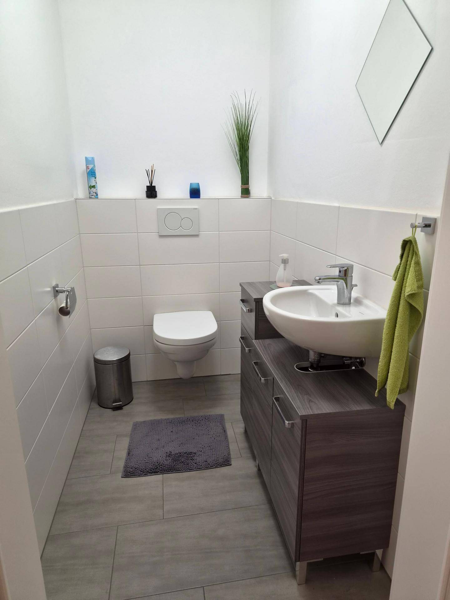 Kleines Gäste-WC mit wandhängendem WC, Waschbecken und Fliesenboden.