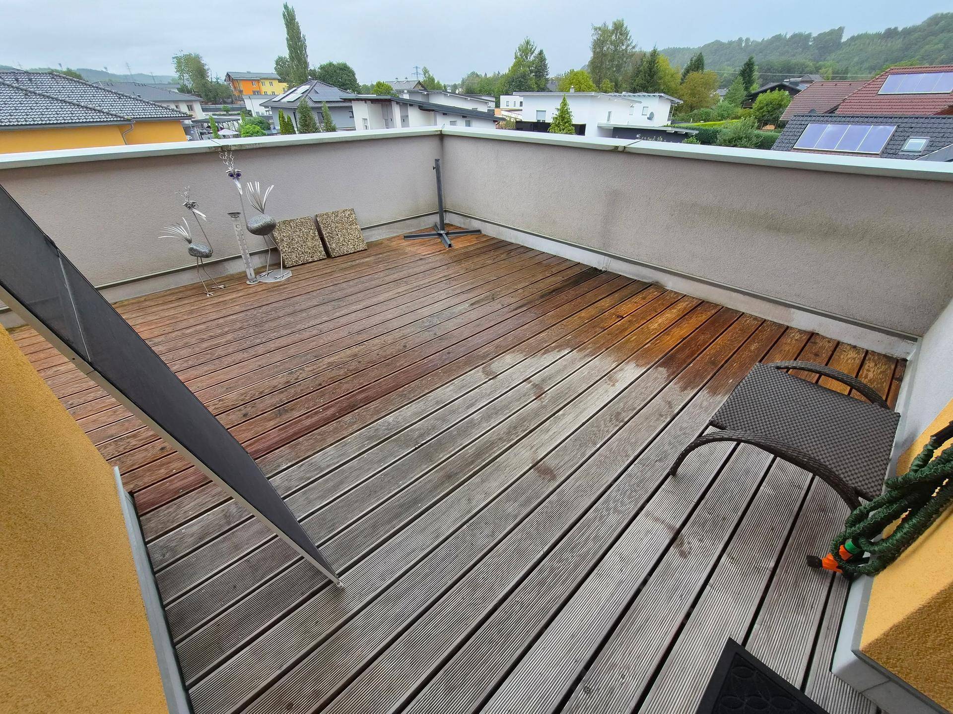 Große Dachterrasse mit Holzboden und Blick auf die umliegenden Häuser.