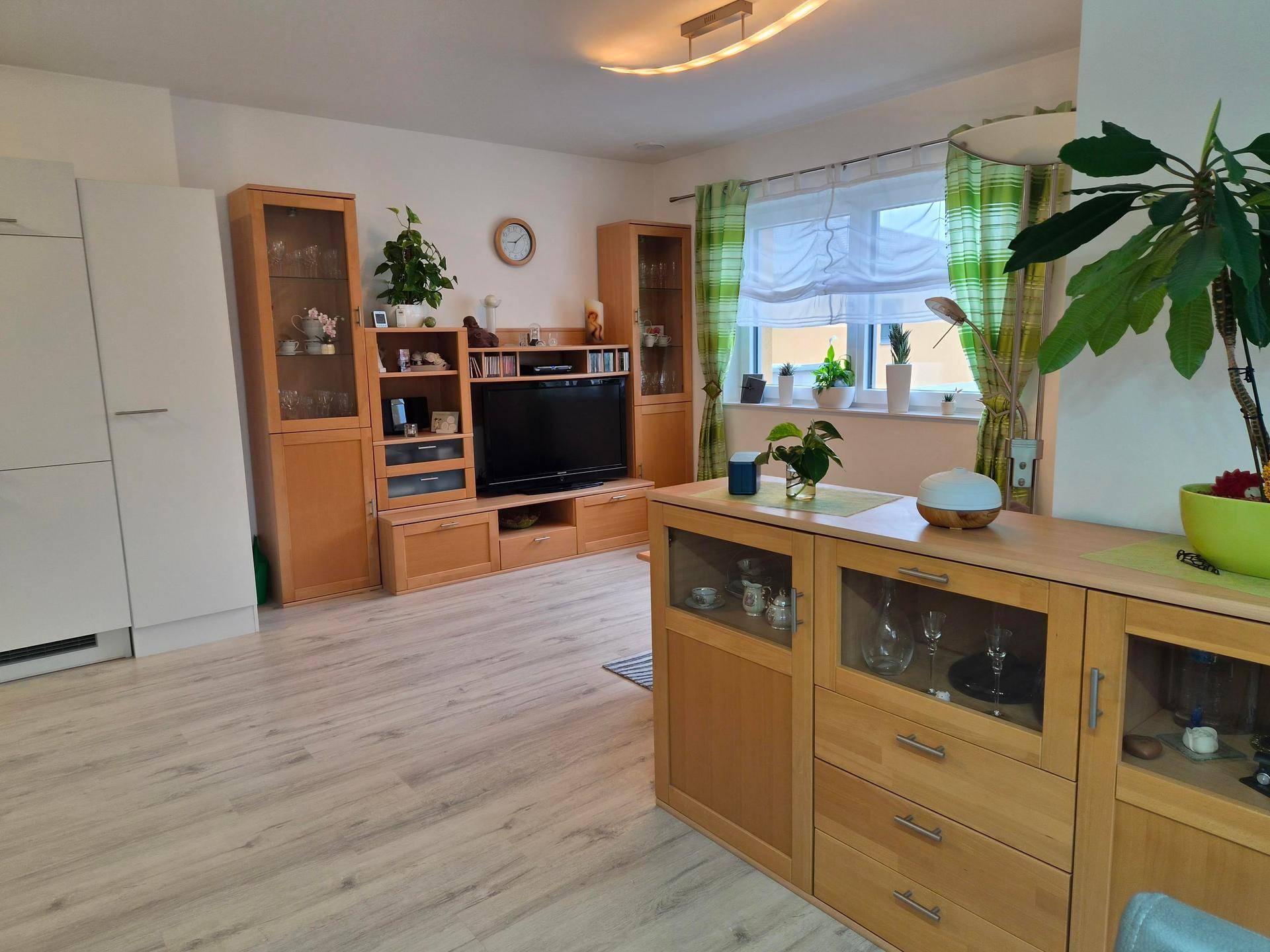 Gemütliches Wohnzimmer mit Holzmöbeln, Laminatboden und Blick auf die Umgebung.