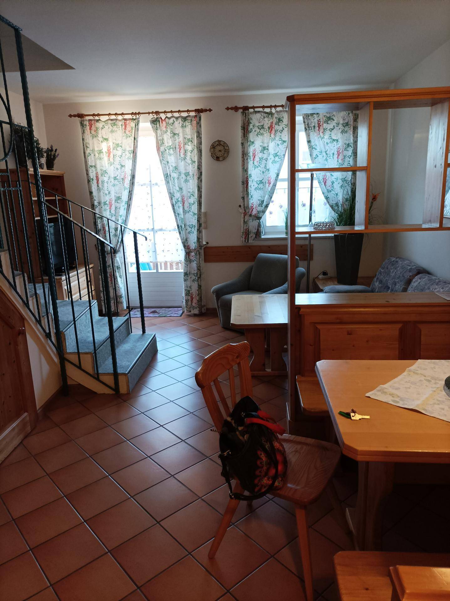 Gemütlicher Wohn- und Essbereich mit Holzmöbeln, Terrakottafliesen und Zugang zum Balkon.