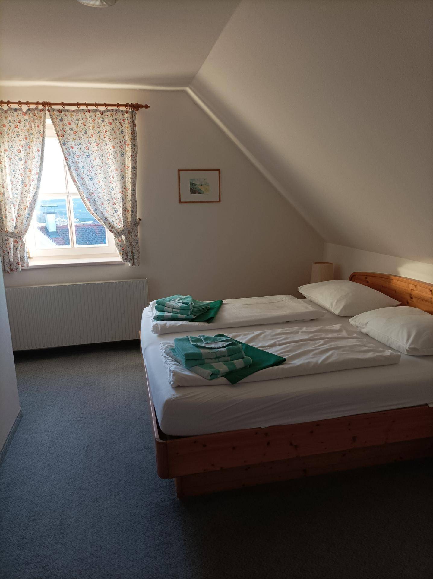 Schlafzimmer im Dachgeschoss mit Doppelbett, Teppichboden und schrägen Wänden unter dem Dach.