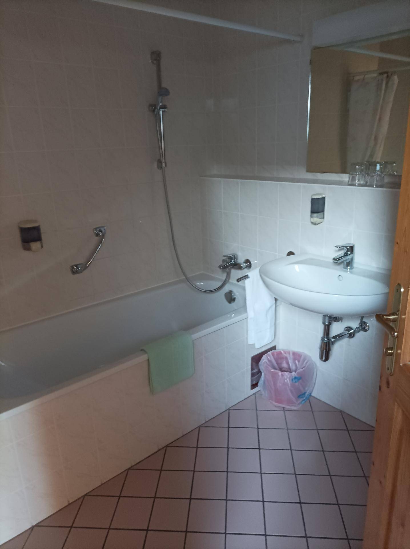 Helles Badezimmer mit Badewanne, Waschbecken und hellen Fliesen im Stil der 80er Jahre.