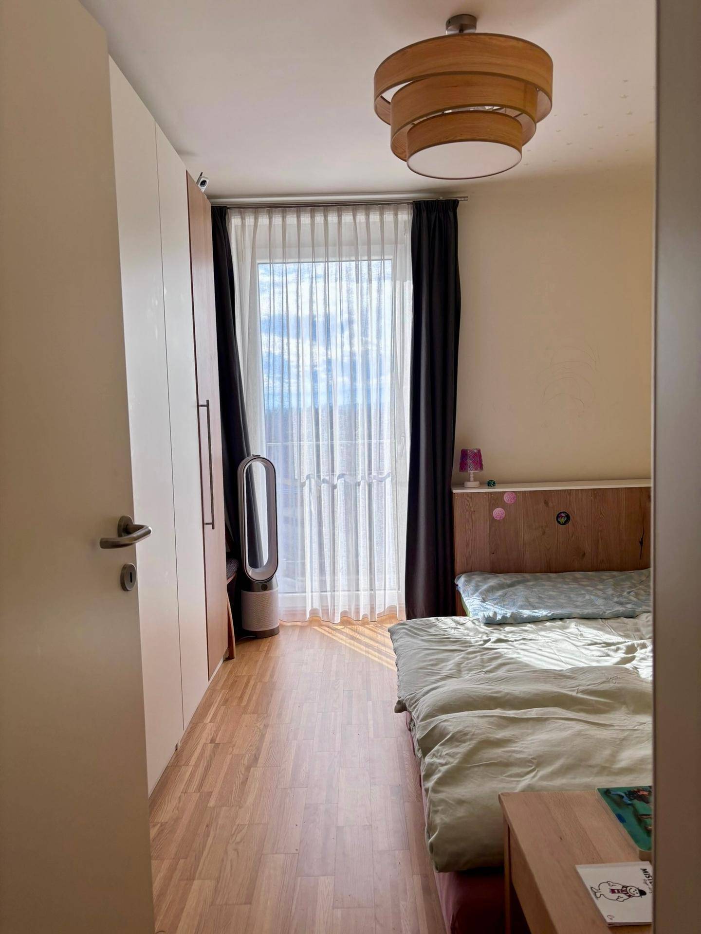 Schlafzimmer mit Doppelbett, Kleiderschrank und großem Fenster für viel Tageslicht.