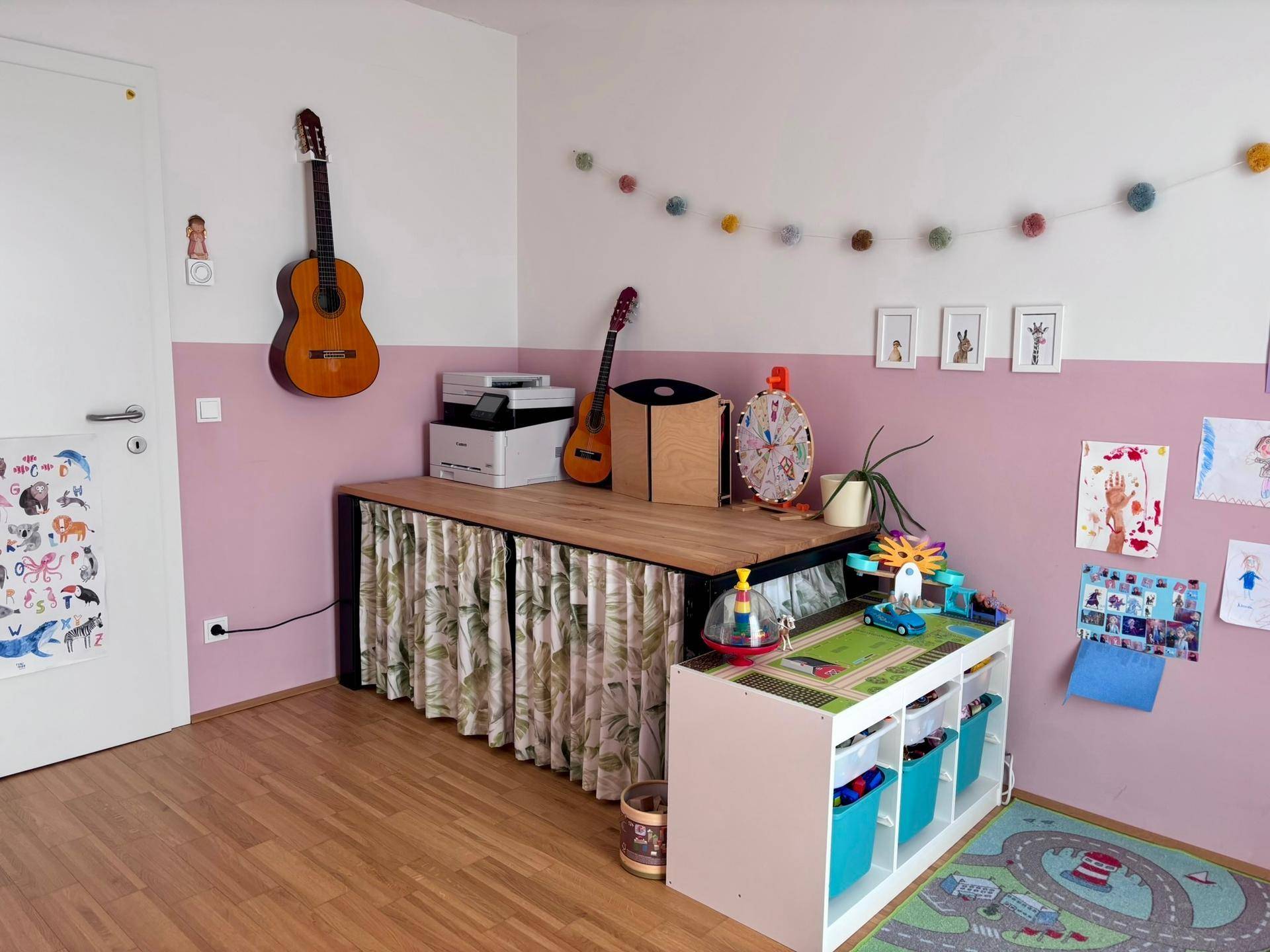 Kinderzimmer mit Gitarre an der Wand, rosa Akzentwand und Holzmöbeln.