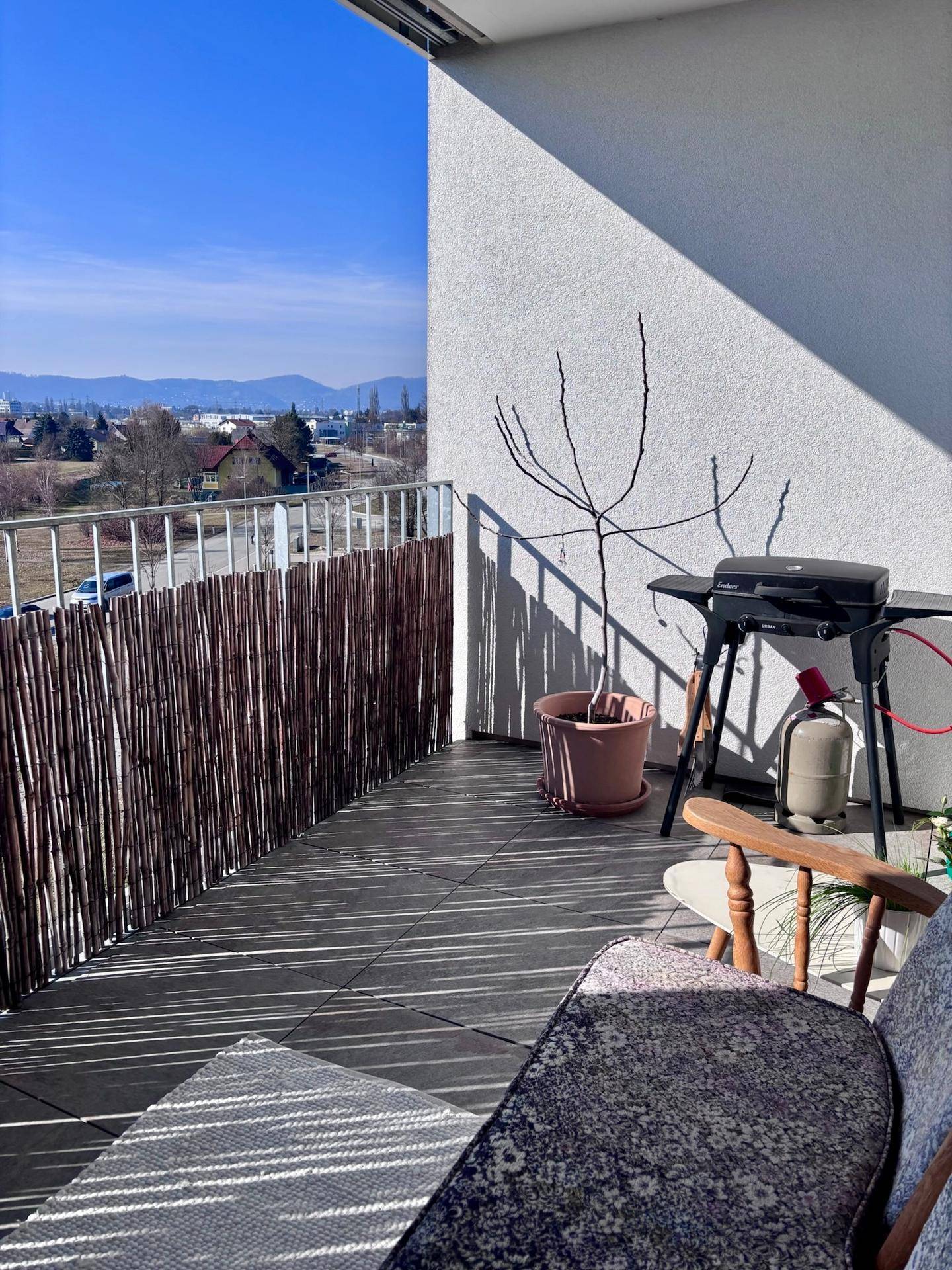 Balkon mit Grillbereich und weitem Blick über die Landschaft und Berge.