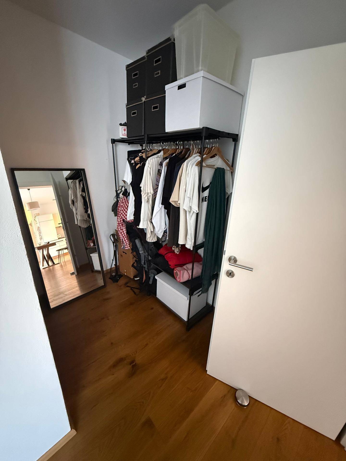 Begehbarer Kleiderschrank mit offener Garderobe, Stauraum und großem Spiegel.